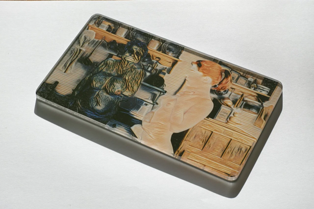 A metallic rectangular box with an artistic, digitally painted image of a dog and a woman in a kitchen.