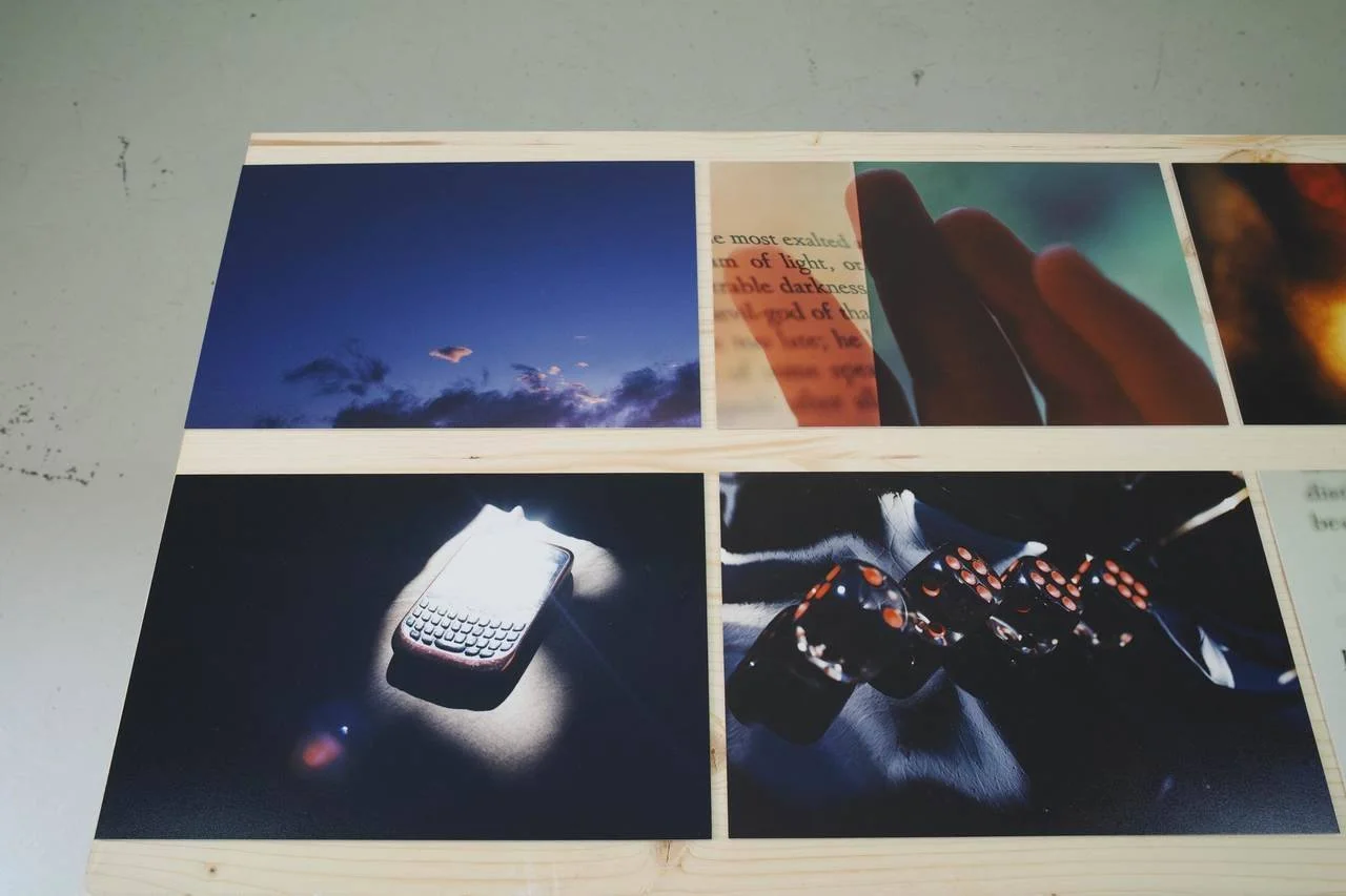 Four photographs arranged on a wooden surface. The top-left photo shows a blue sky with clouds at dusk. The top-right photo displays a person holding a cellphone with a page of text overlay, partially obscured by fingers. The bottom-left photo featur