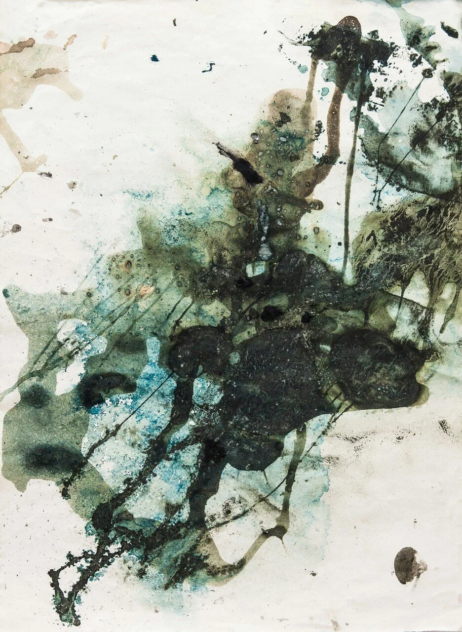 Abstract watercolor painting with black, blue, and green splashes and drips on white paper.