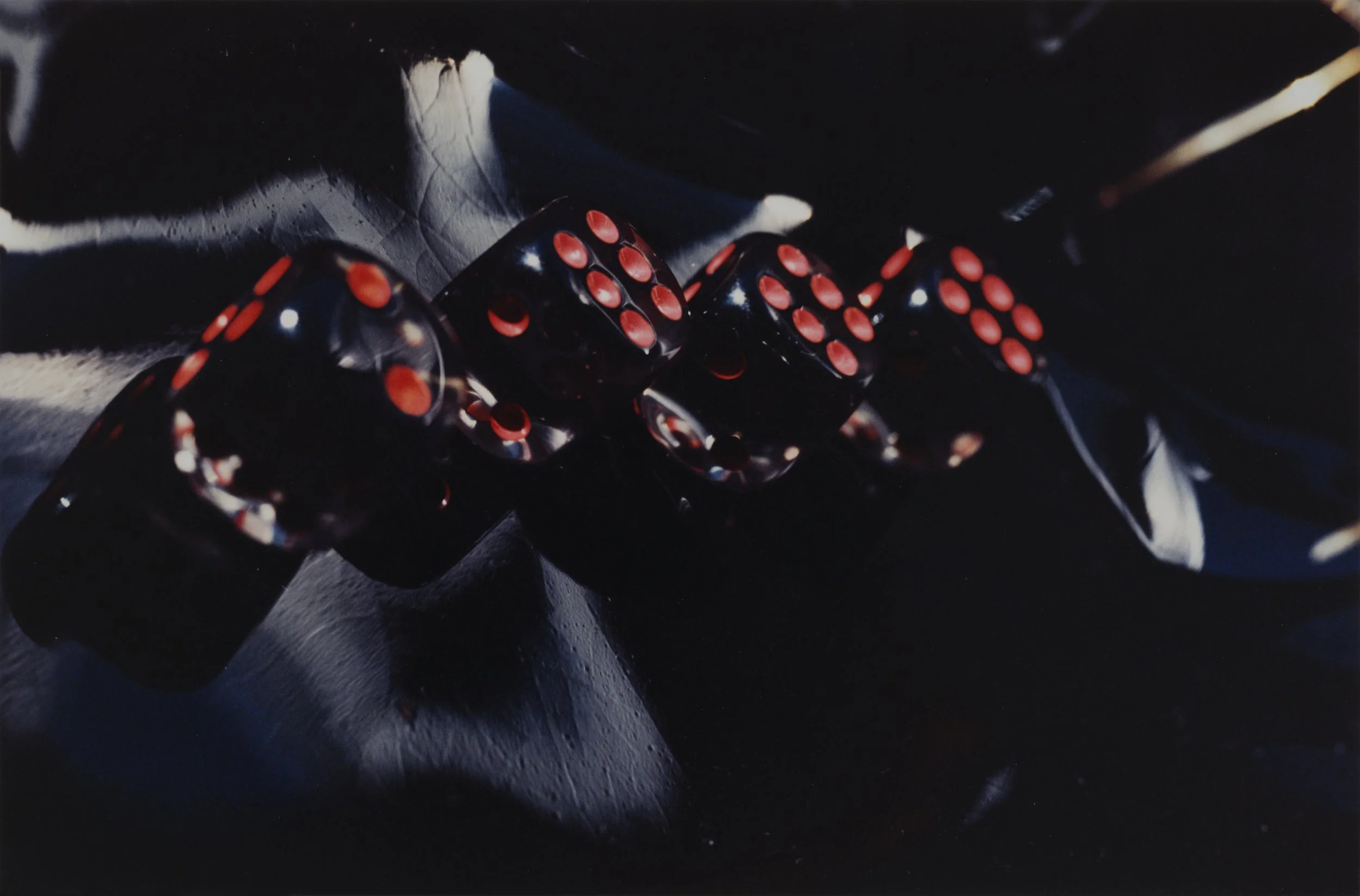 Close-up of black dice with red pips, scattered on a dark surface forming the title 2666.