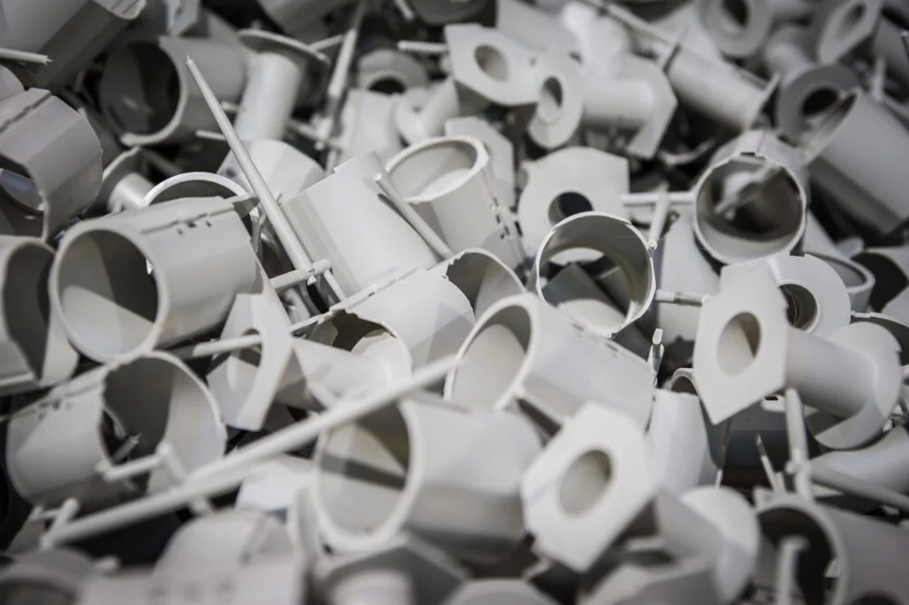 Pile of white plastic electrical conduit fittings and connectors.