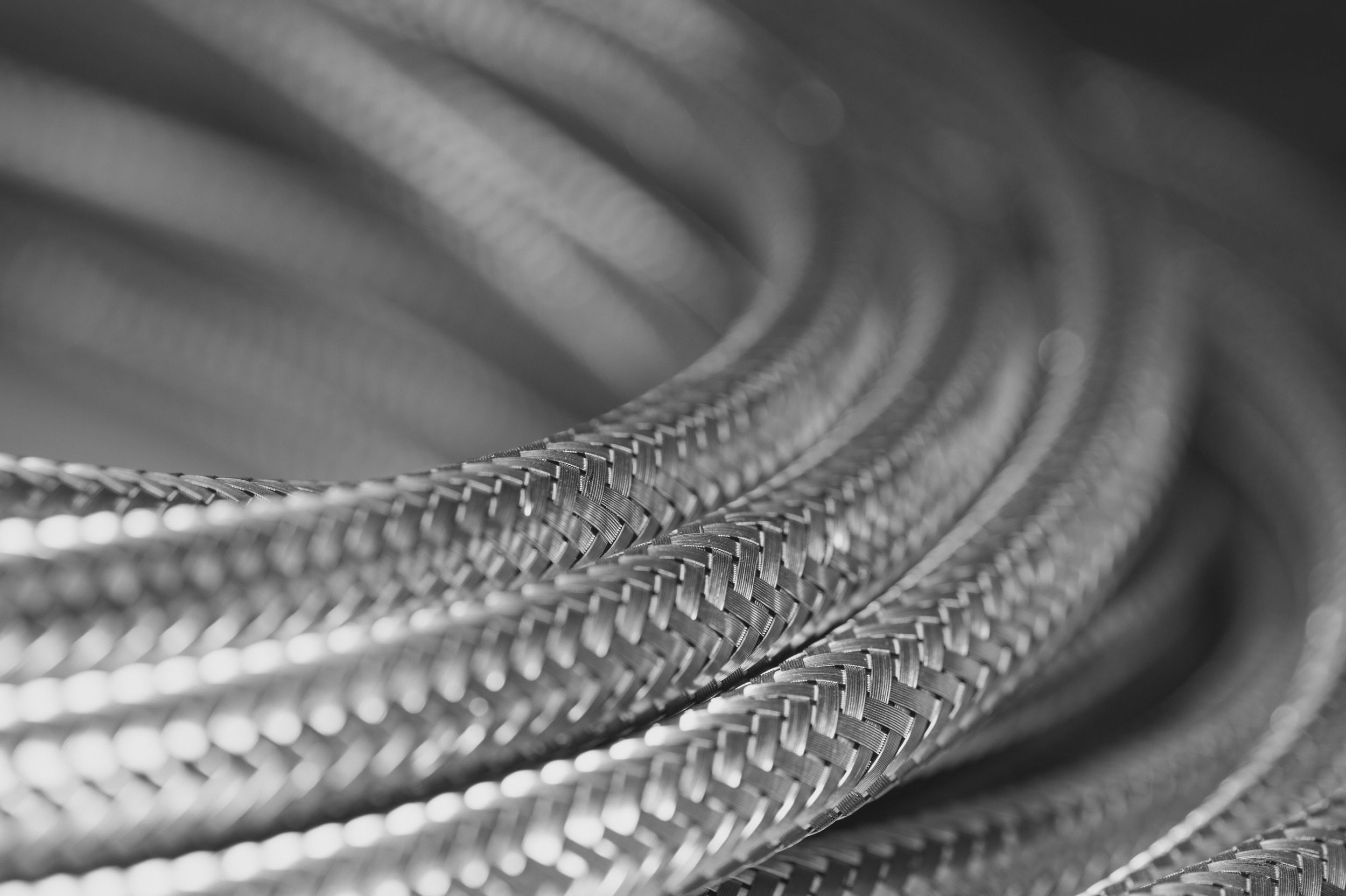 Close-up of coiled metallic braided hoses or cables, black and white