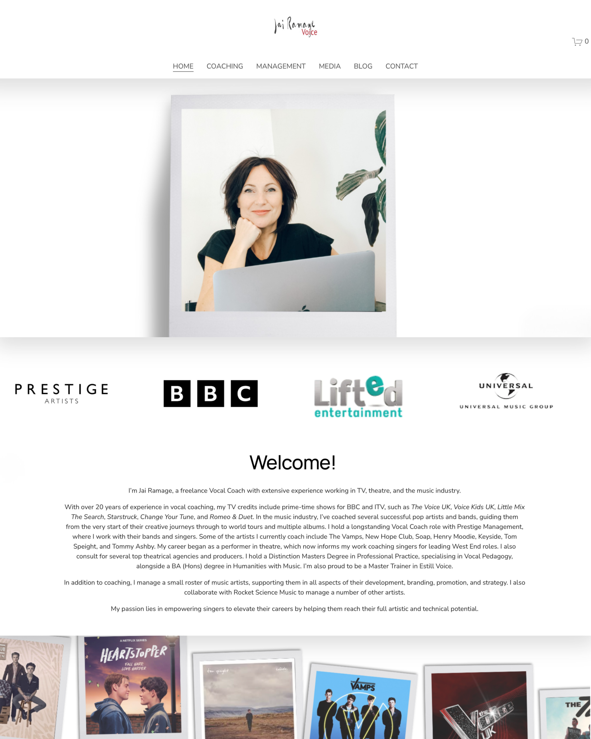 A woman with short dark hair smiling while sitting at a desk with a laptop. She wears a black top, and there’s a green plant beside her.