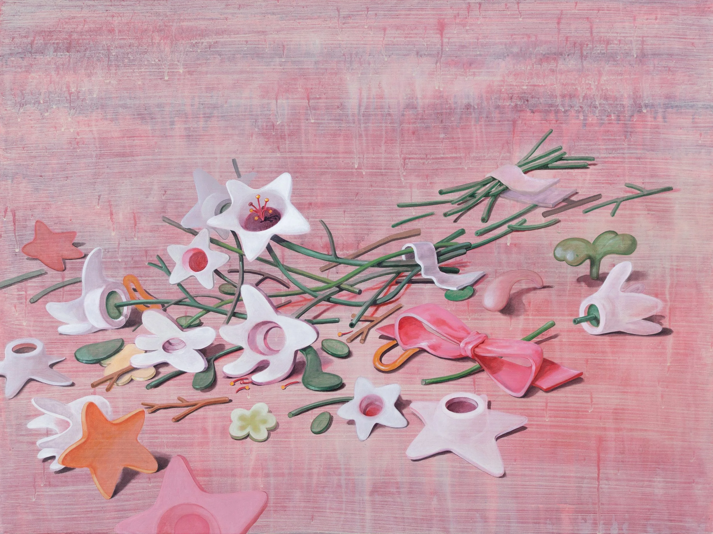 A scattered assortment of decorative flower-shaped and star-shaped ceramic or plastic jewelry charms in pink, white, orange, and green on a pink wooden surface, with some charms attached to green stems and a pink ribbon tied in a bow.