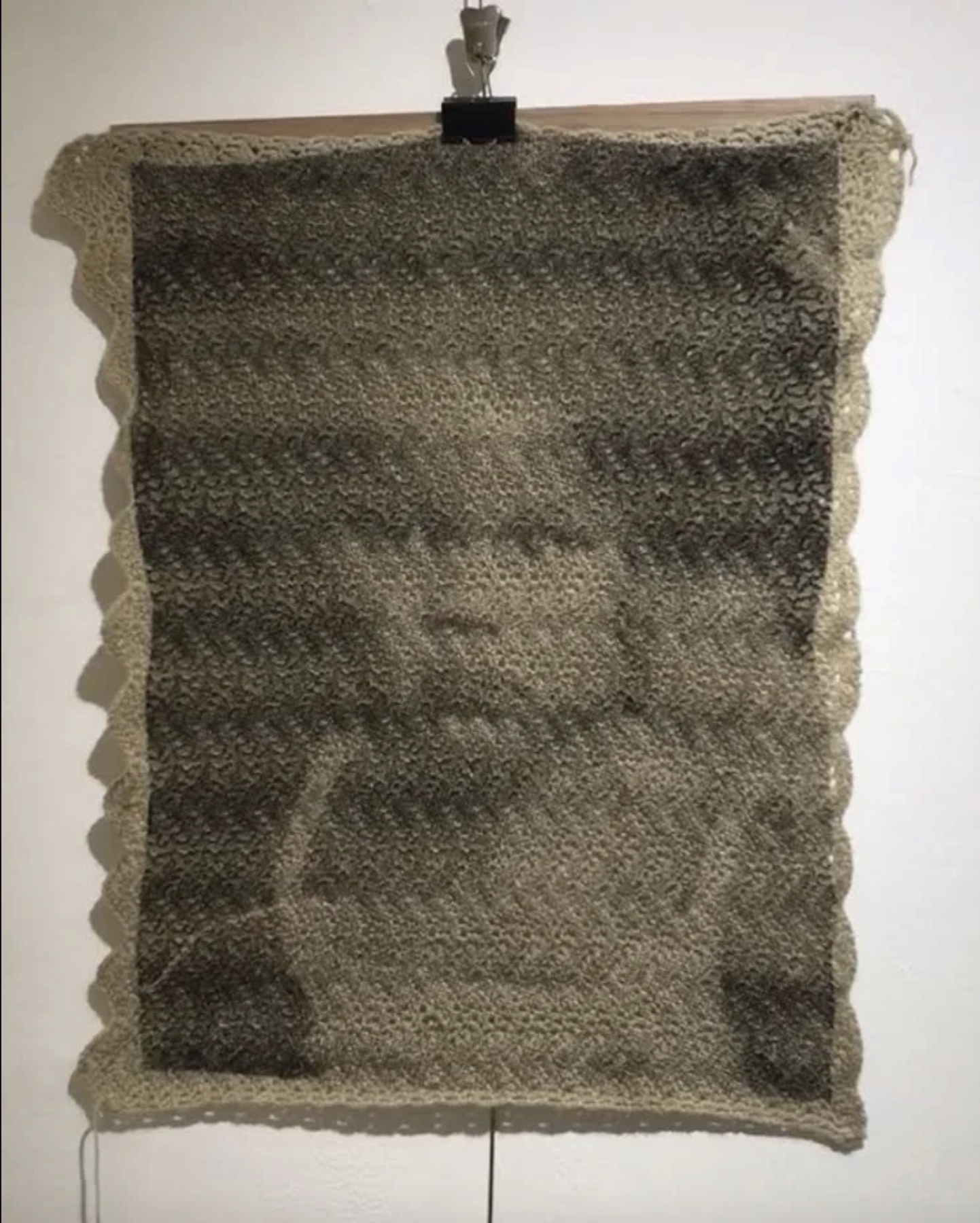 Textile artwork resembling a monochrome portrait of a person's face.