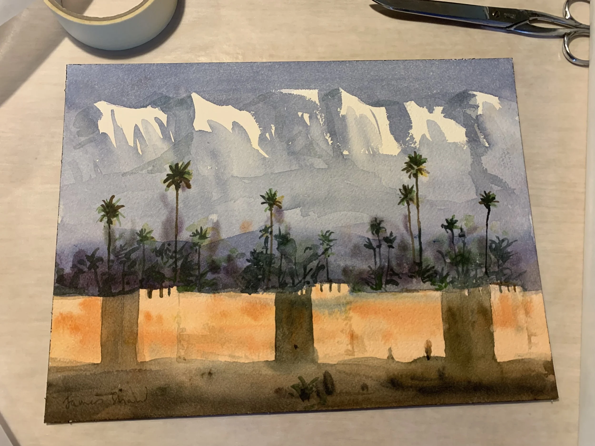 Watercolor painting of palm trees in front of a mountain range at sunset.