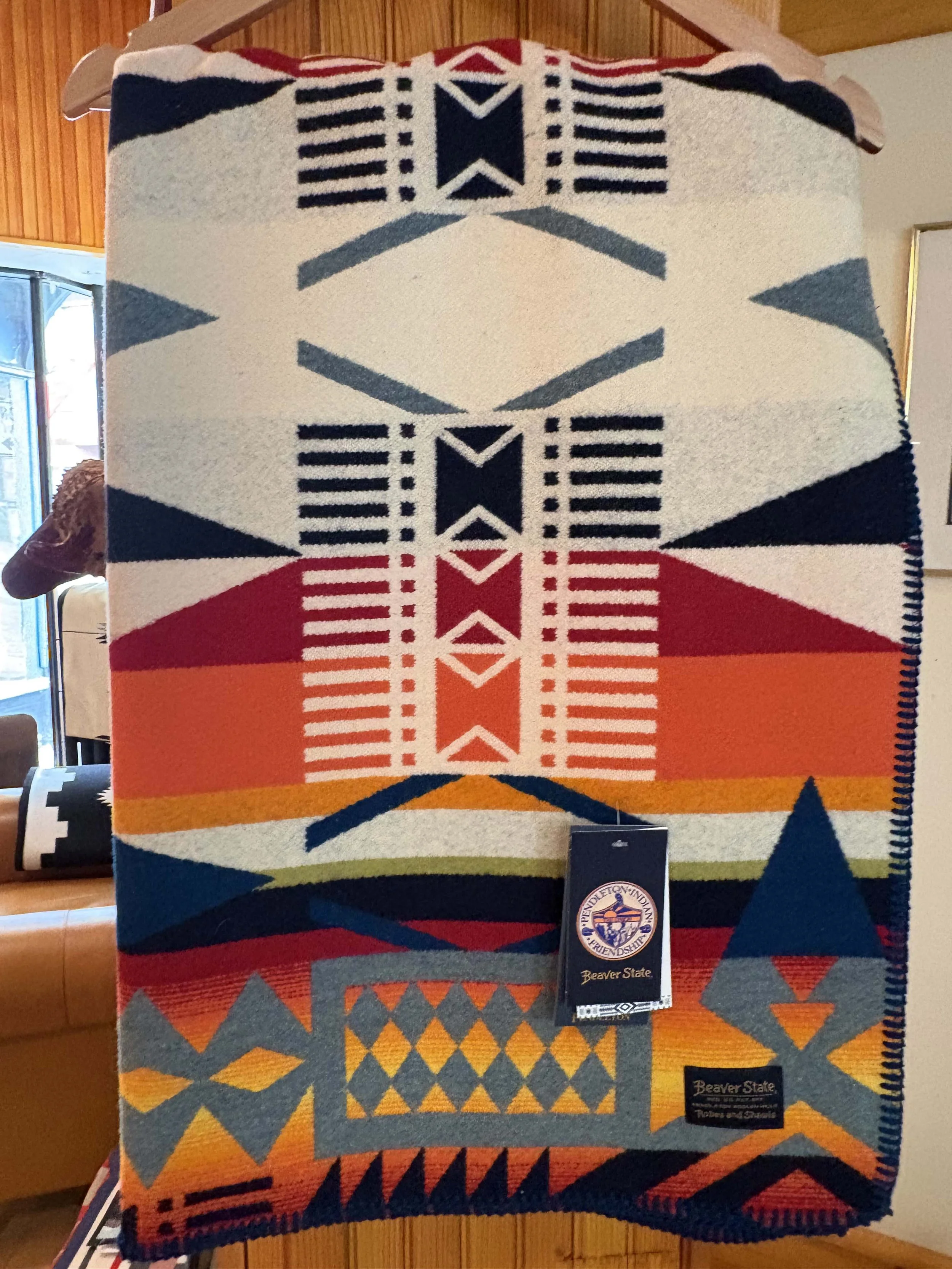 Colorful woven blanket with geometric patterns and the Beavers State logo attached.