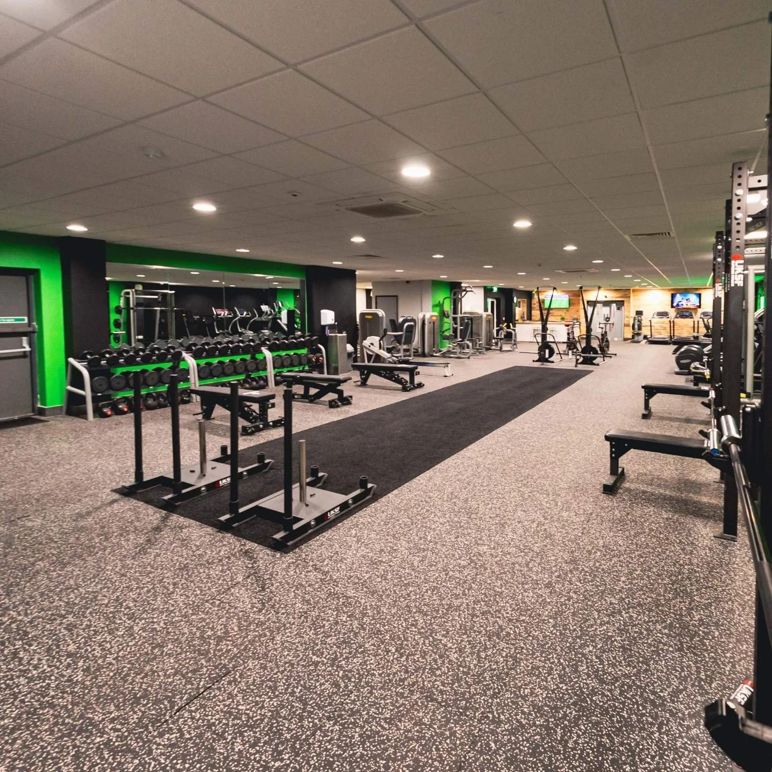 Interior of The Gym Lab with various weightlifting, cardio, and workout equipment, neatly organised with a black and green colour scheme and a speckled rubber floor.
