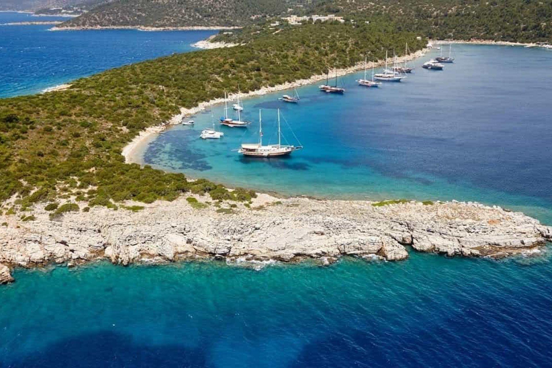 Luxury yacht anchored off Papuc Burnu in Bodrum, surrounded by crystal-clear turquoise waters, dramatic rocky coastline and the unspoiled beauty of the Aegean Sea.