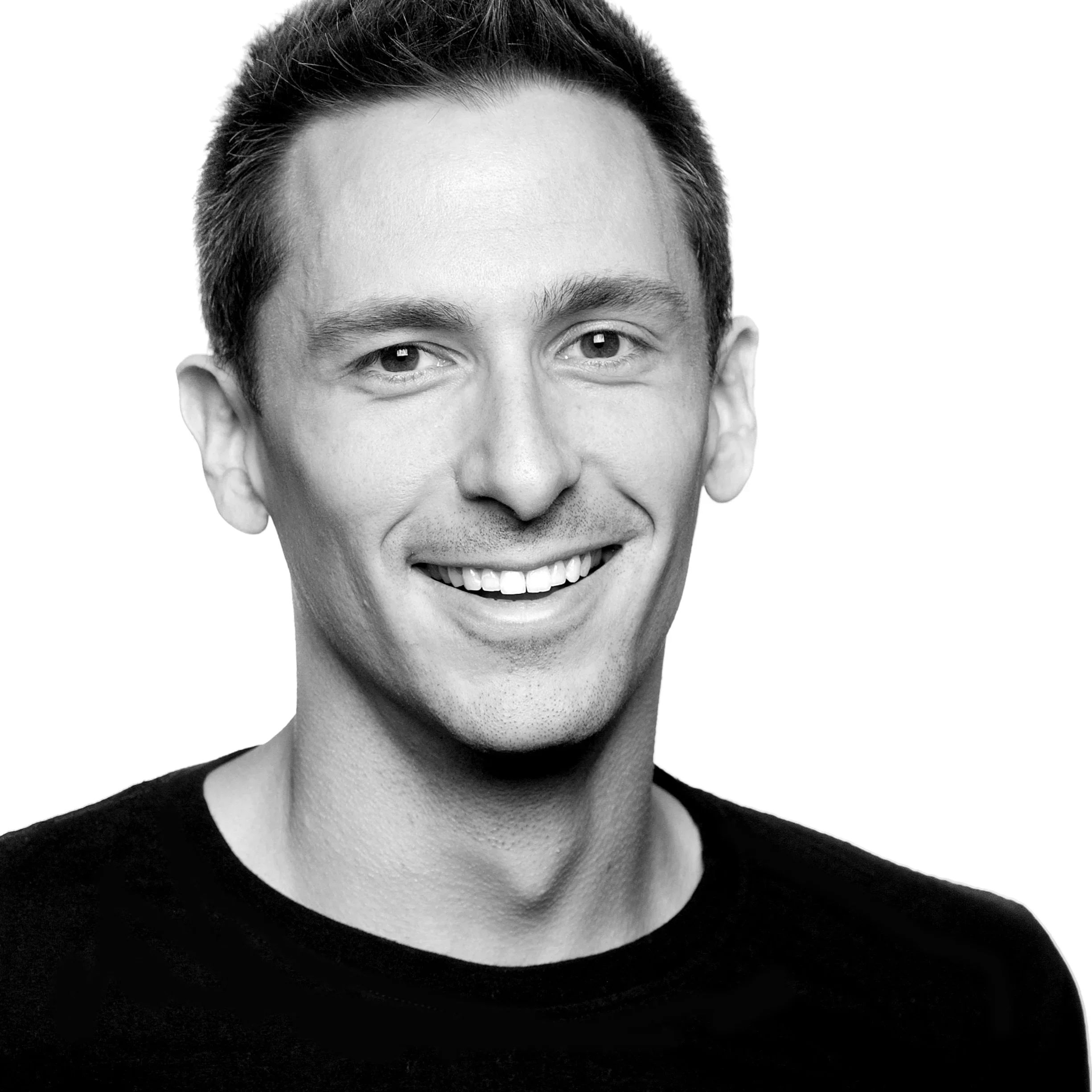 Black and white portrait of a smiling man with short dark hair, wearing a black shirt, against a plain background.