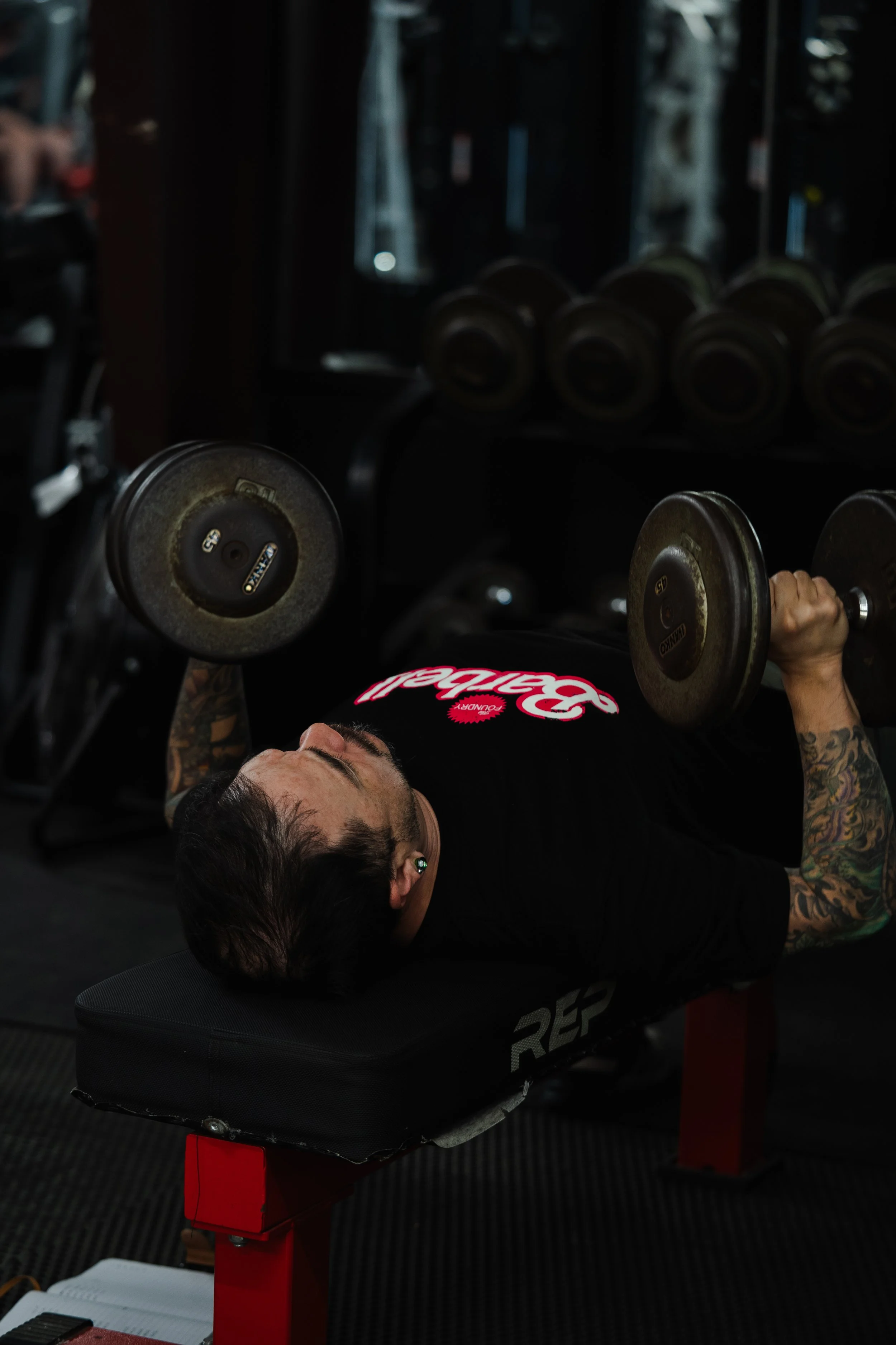 Member performing a dumbbell bench press at The Foundry Barbell in Greenville, NC
