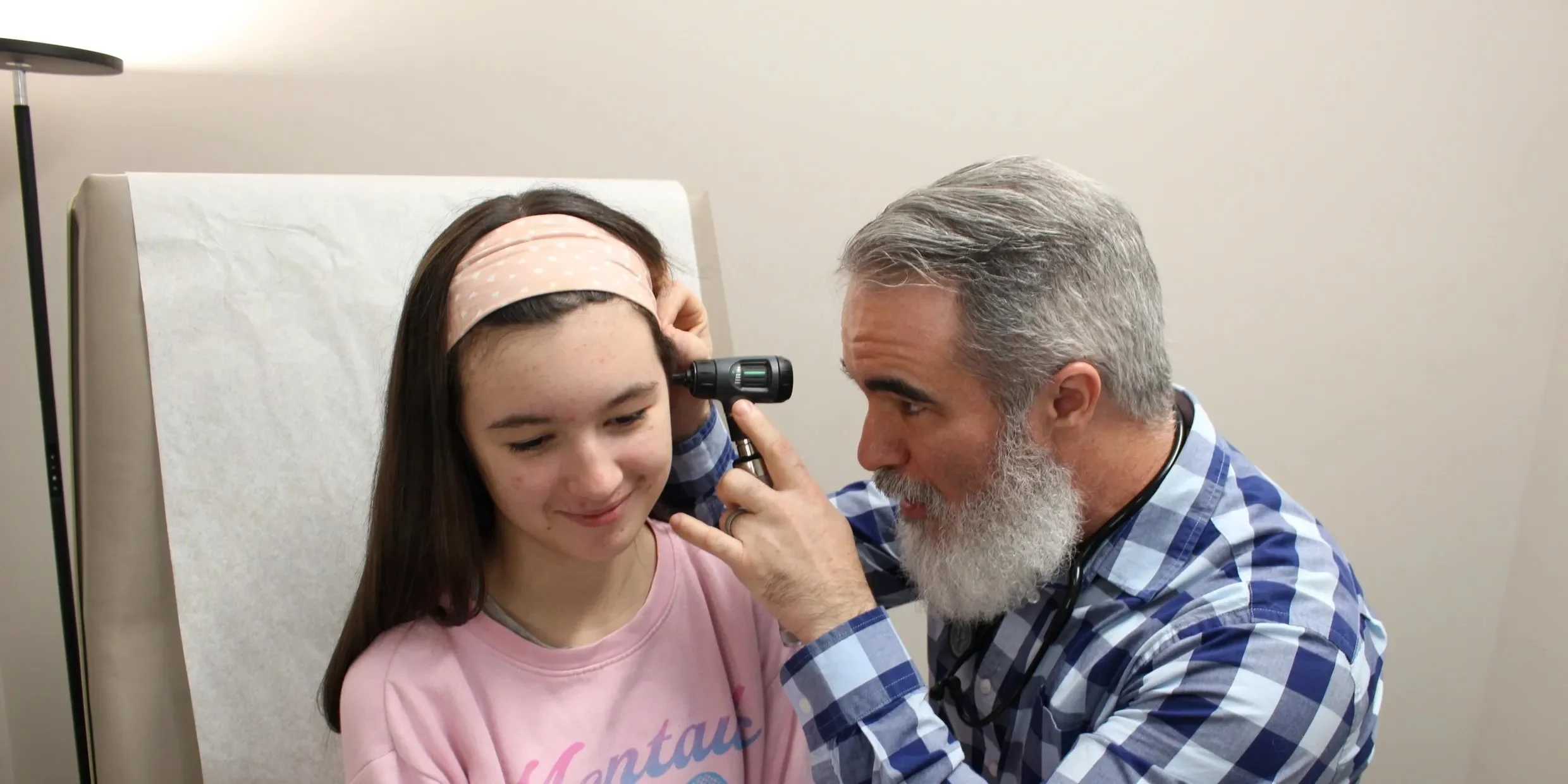 A doctor examining a girl with an otoscope in a medical office.