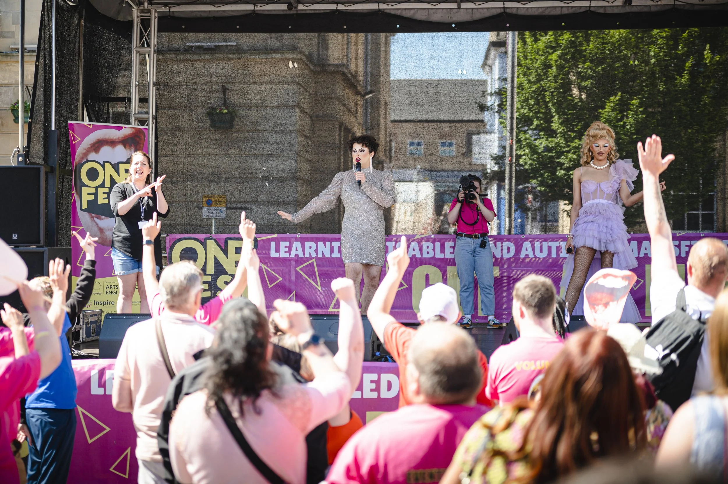 Drag act performing on a stage to a crowd of people