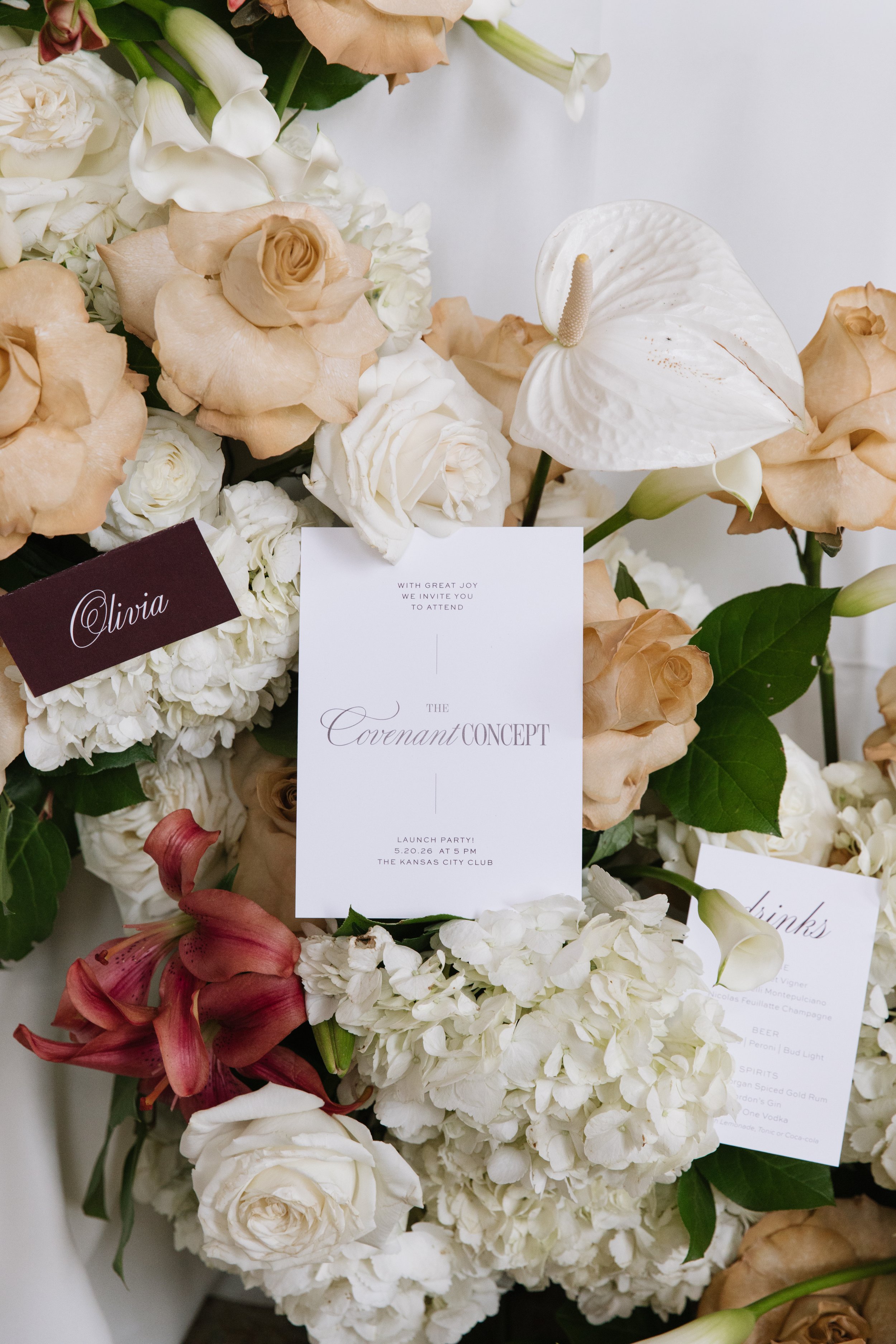 Wedding invitation suite styled with white florals, roses, and curated event details