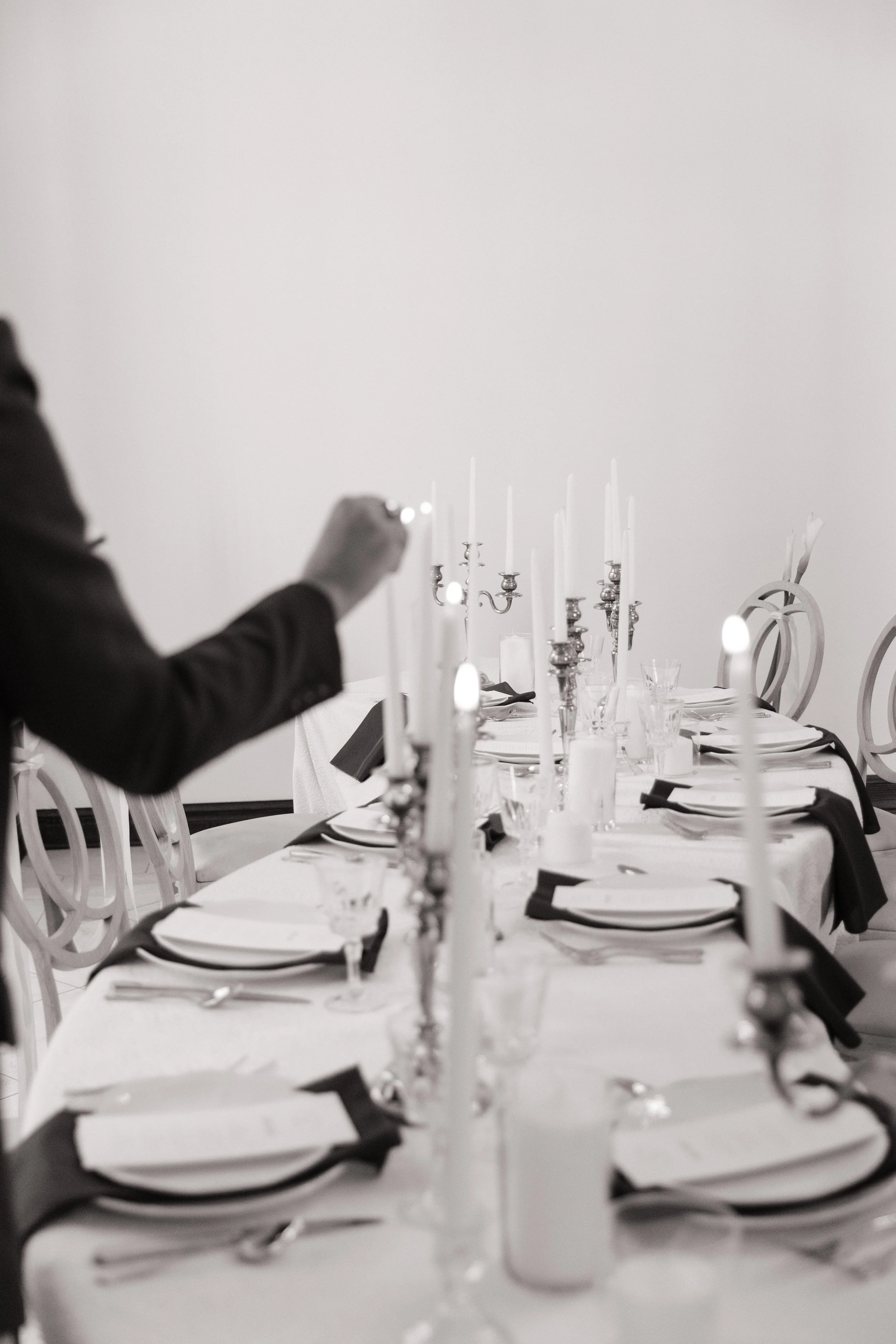 Elegant candlelit reception table setting with layered place settings and modern décor