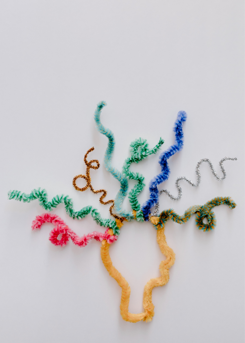 Colorful pipe cleaners arranged in a tree-like pattern on a white background.
