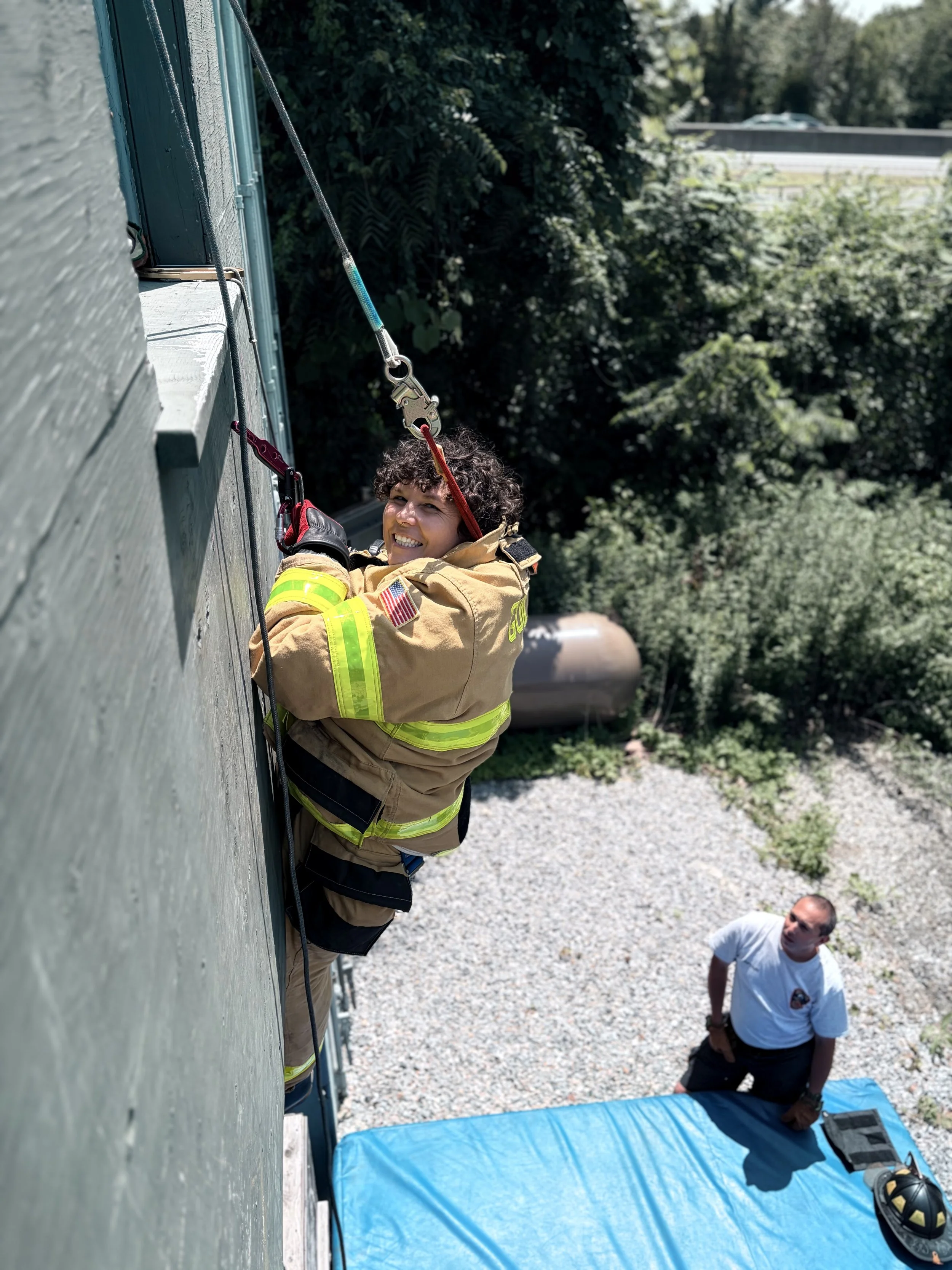 Firefighter in uniform working with climbing safety gear on a building exterior