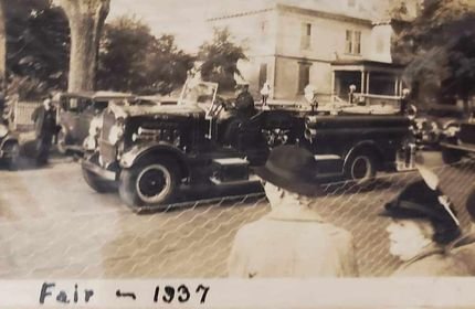 Vintage photo of trucks and people at a fair, 1937.