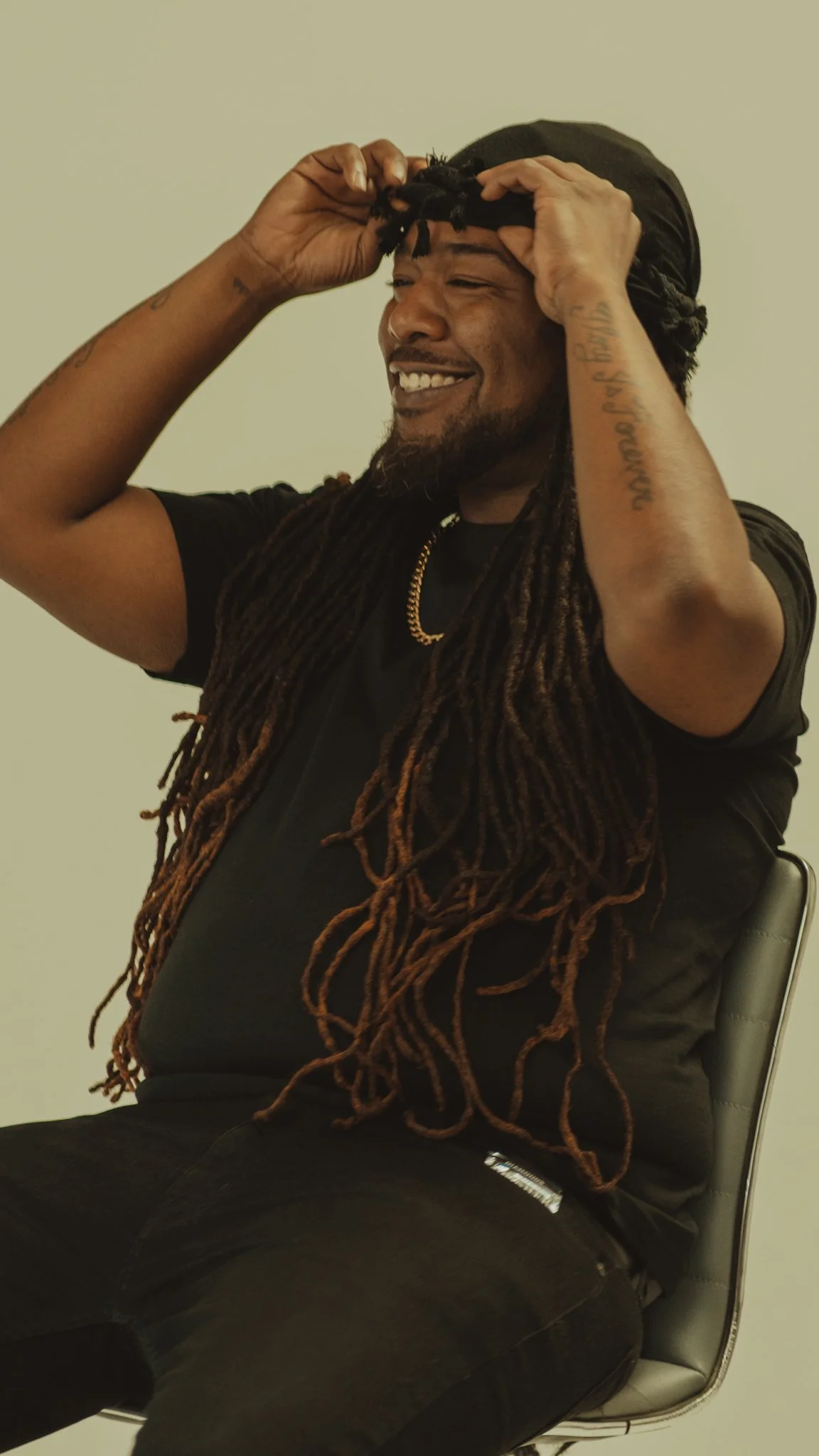 A man with long dreadlocks and glasses singing into a microphone in a recording studio.