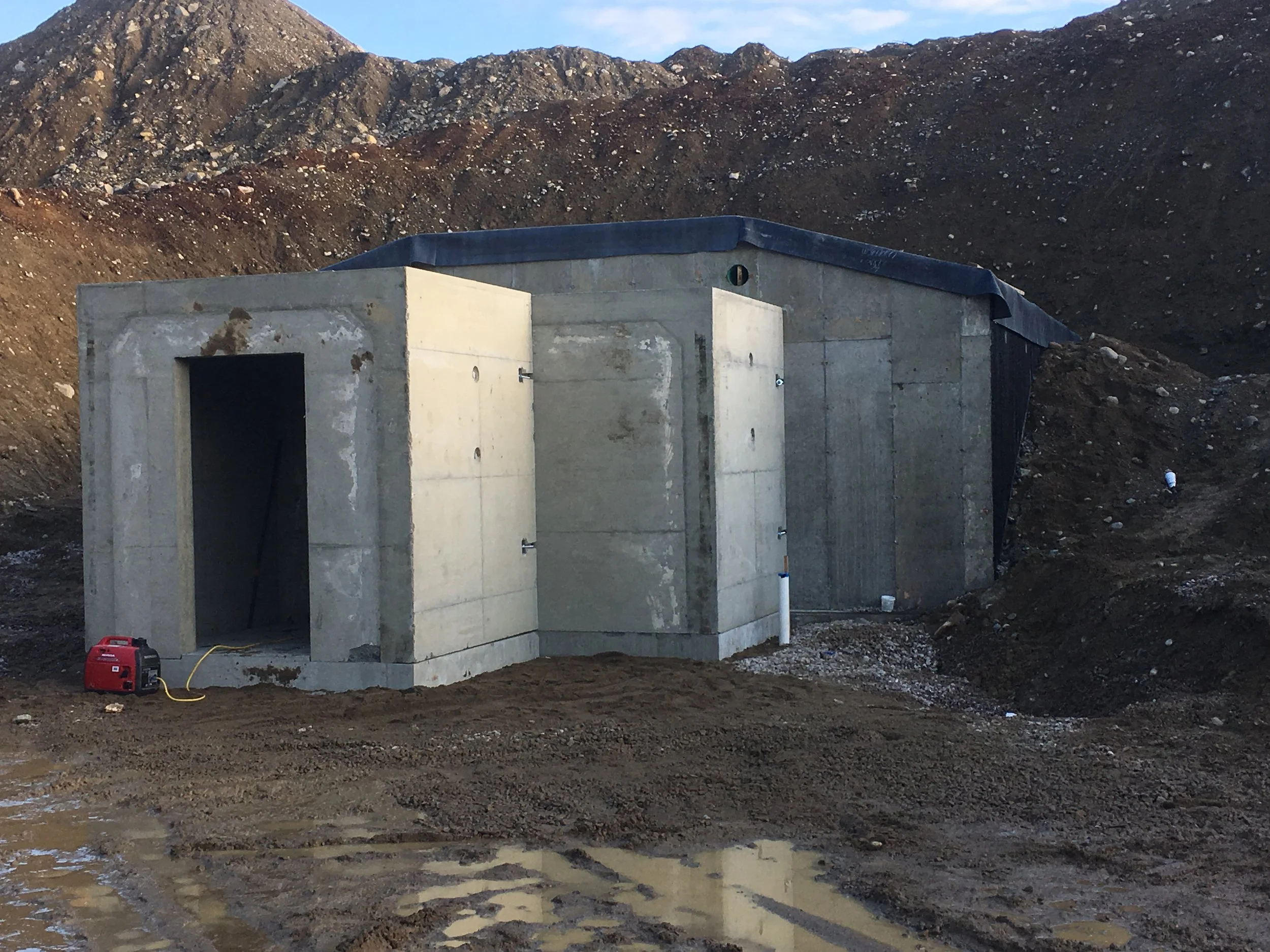 Concrete structure at a construction site with soil and mountains in the background.