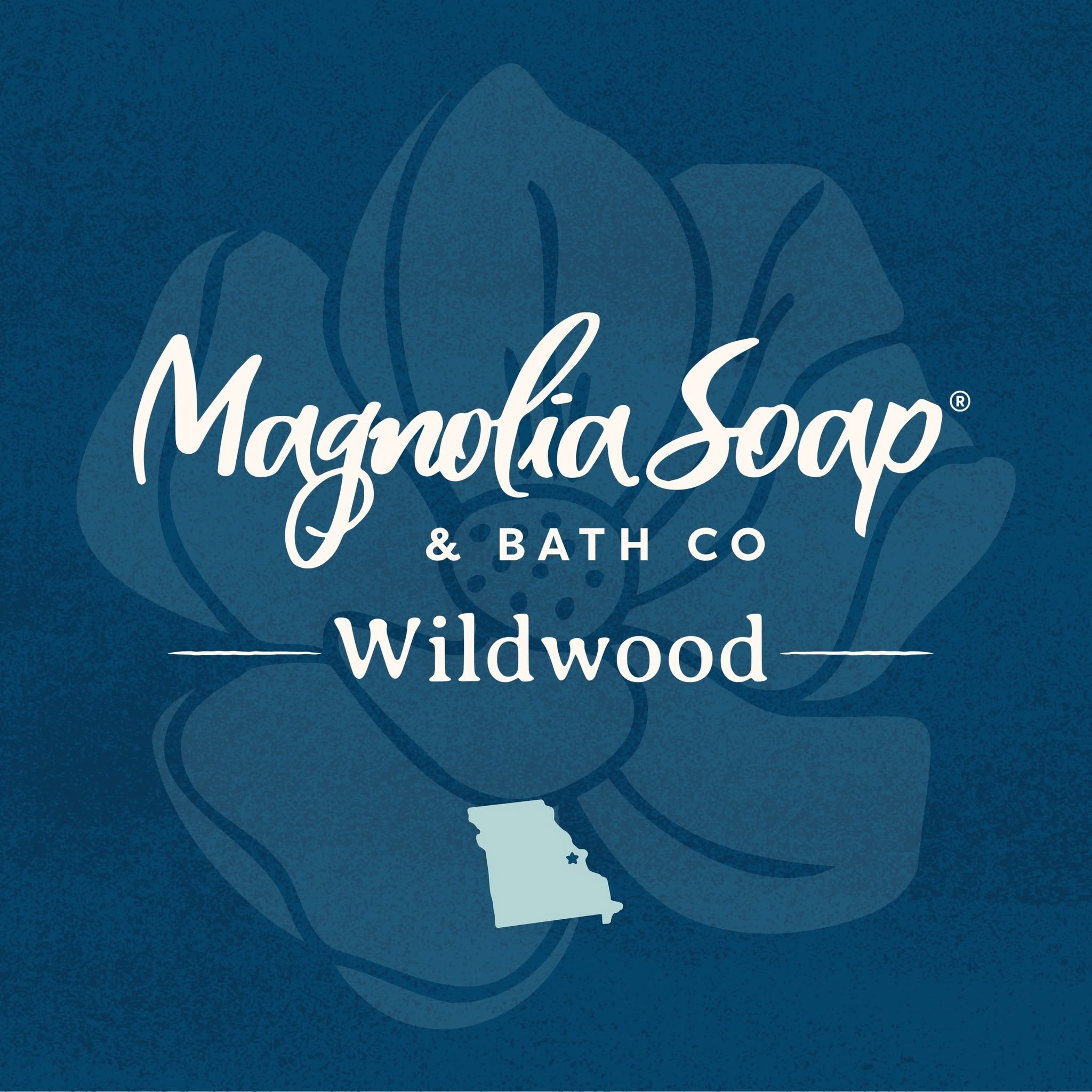 Blue background with white cursive text that says 'Magnolia Soap & Bath Co.' and a faint outline of the state of Missouri with a star indicating a location within the state.