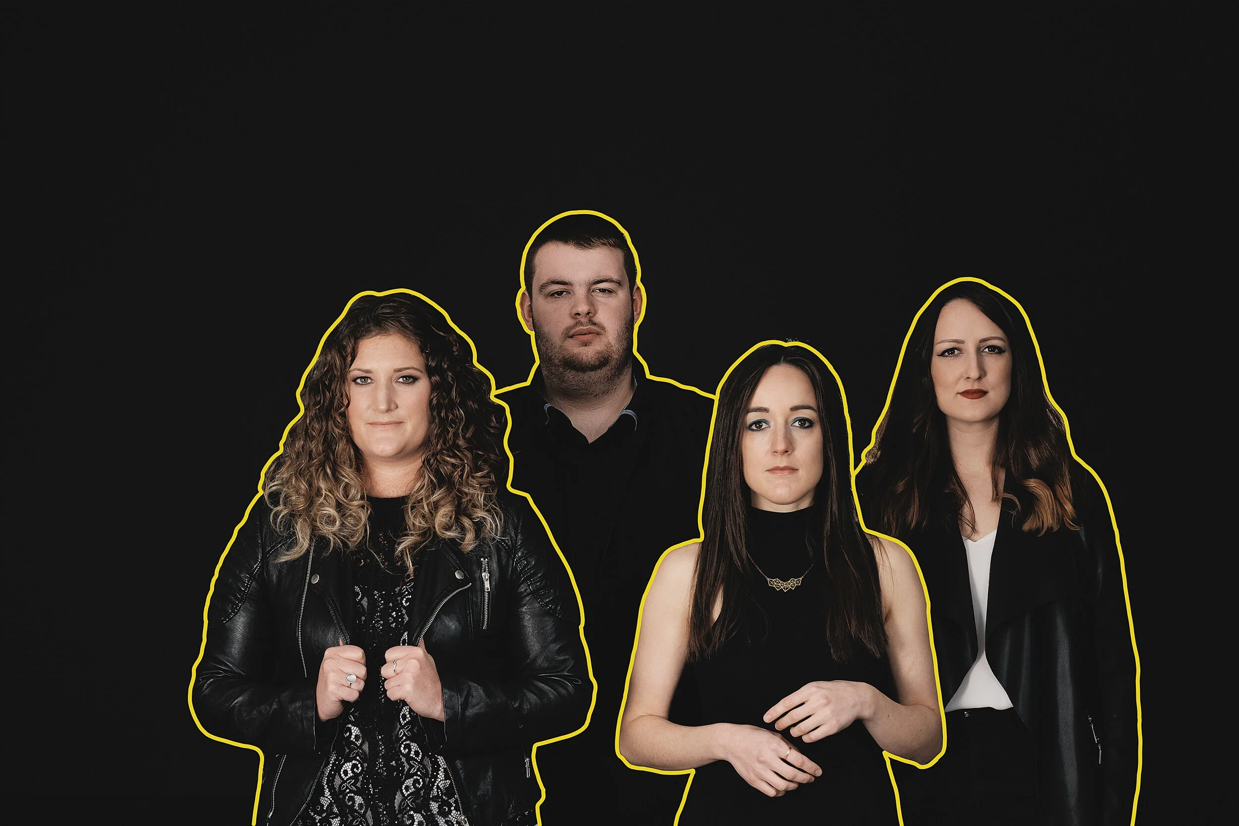 A group of four people with yellow outlines standing against a black background. They are all facing forward, with serious expressions, dressed in dark clothing, with one woman wearing a white top.