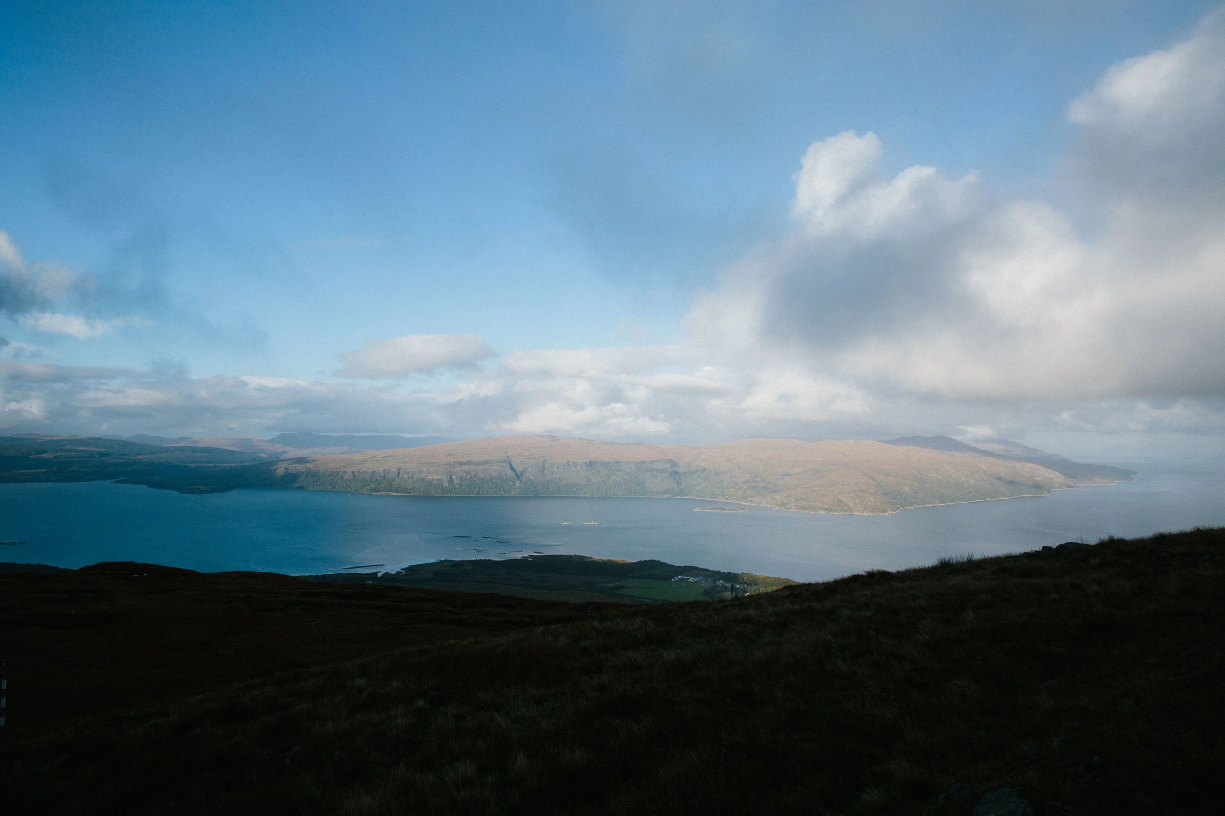 Scenic view of a large body of water with islands and landforms in the distance under a partly cloudy sky.