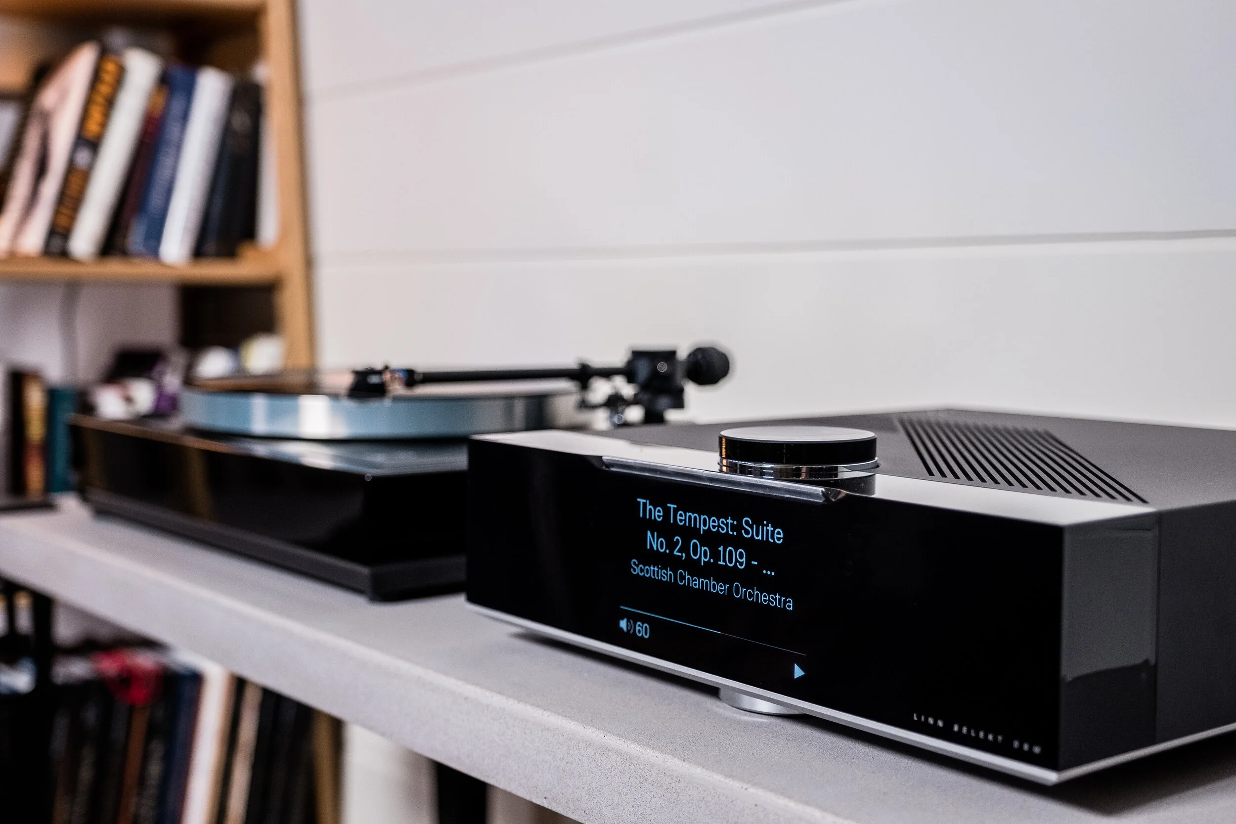 A modern turntable playing music from a digital speaker, which displays the song title "The Tempest: Suite No. 2, Op. 109" by the Scottish Chamber Orchestra.