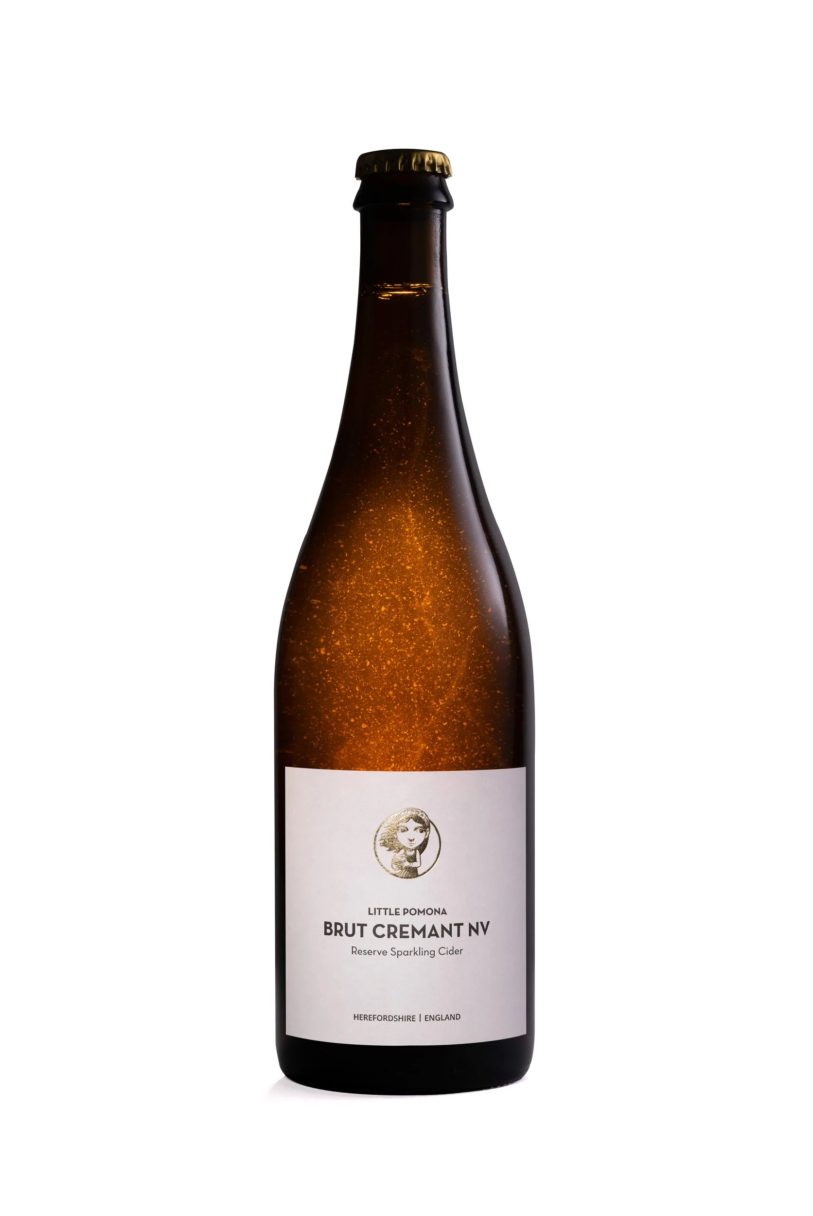 A dark brown glass bottle of Little Pomona Brut Cremant NV reserve sparkling cider with a gold bottle cap, white label with black text, and a small illustration of a girl with curly hair.