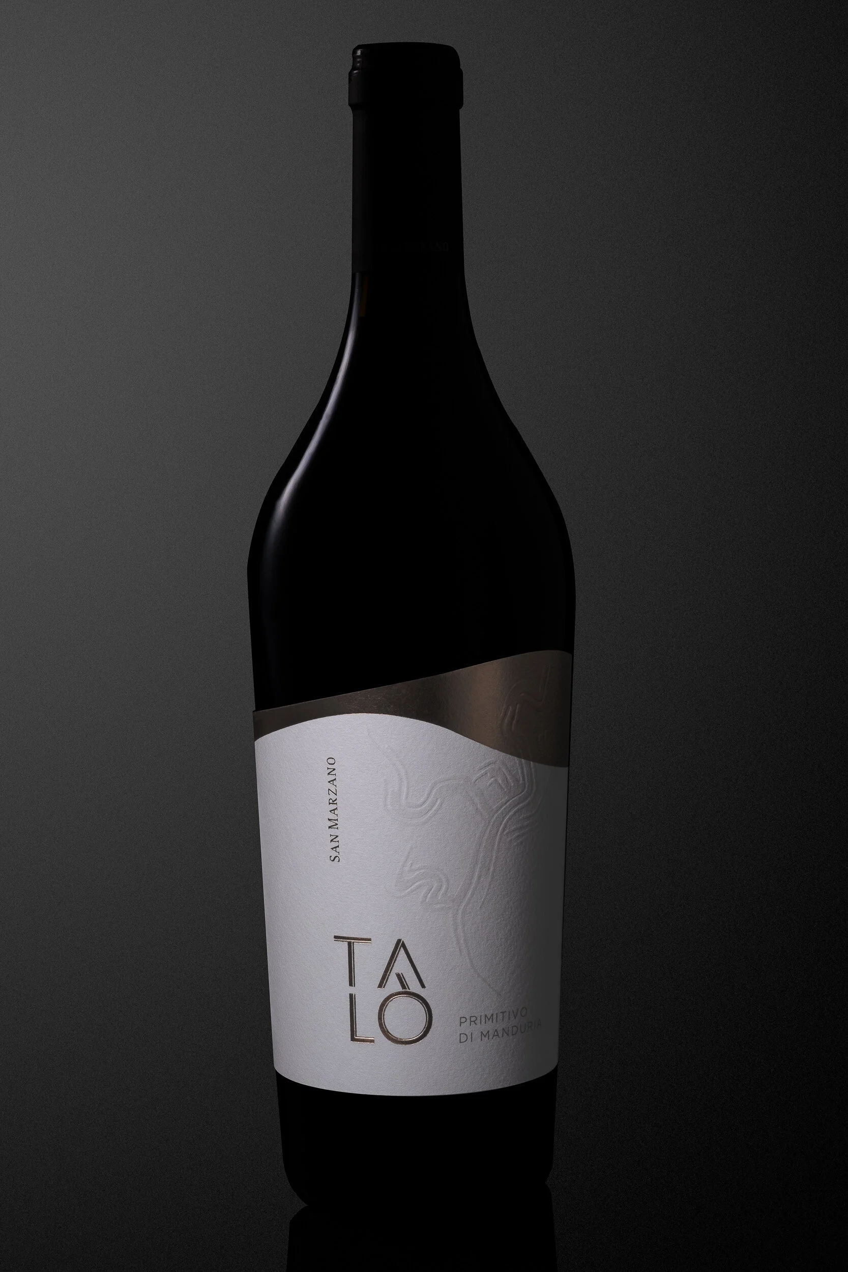 A dark bottle of red wine with a white label and black text, set against a black background.