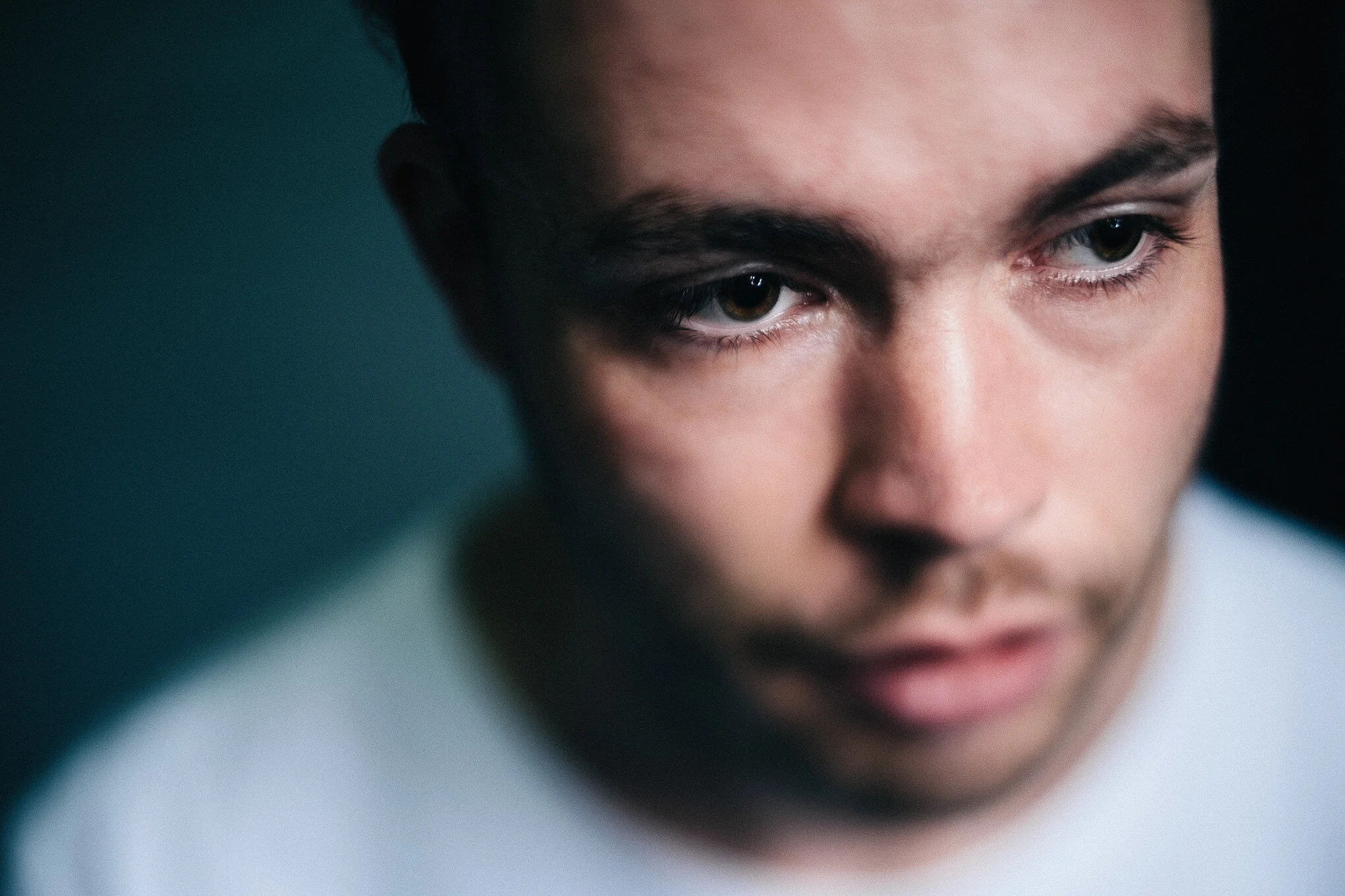 Close-up of a person's face showing intense focus or contemplation, with dark hair and piercing eyes.