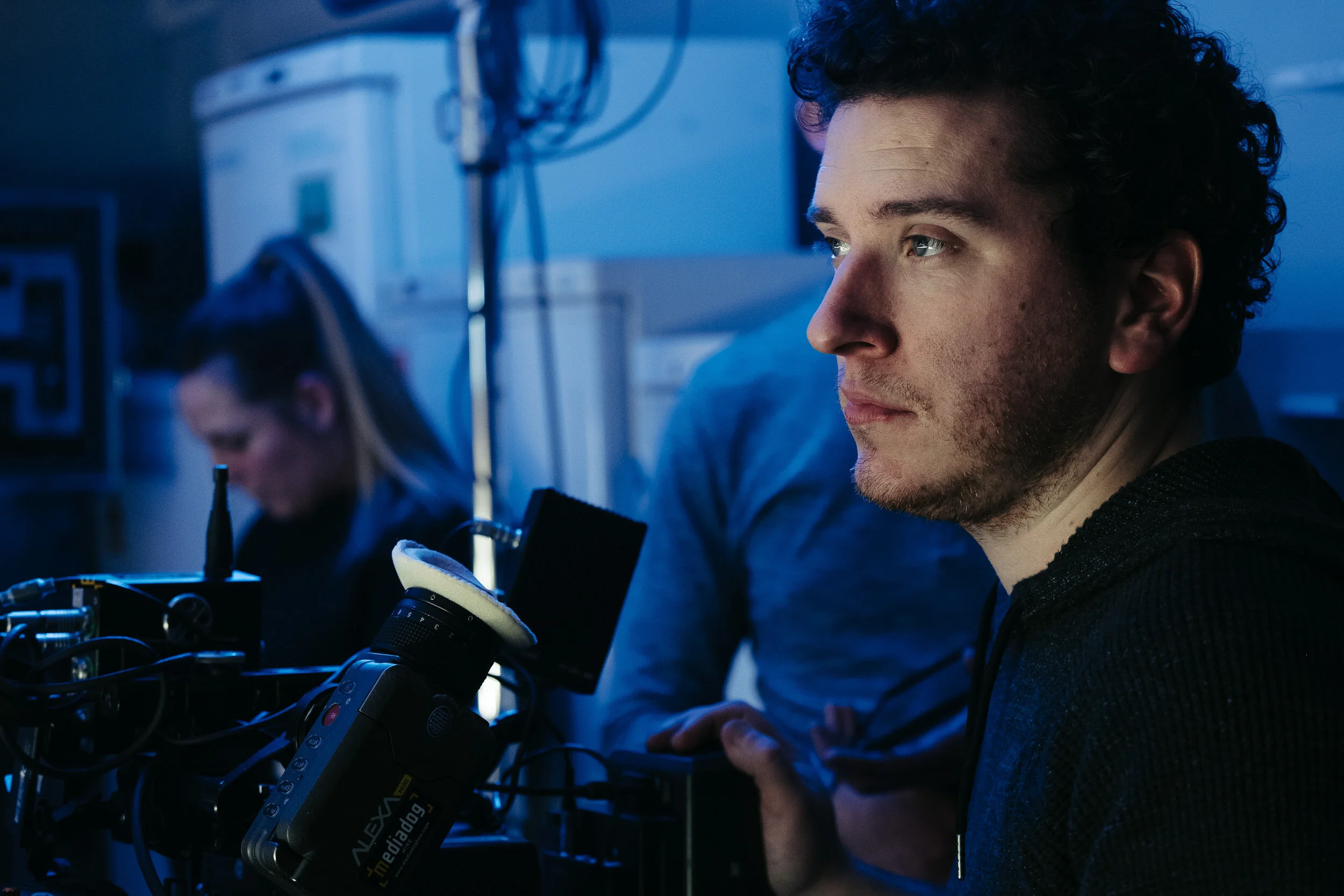 A scientist with curly hair working with a microscope in a laboratory setting.