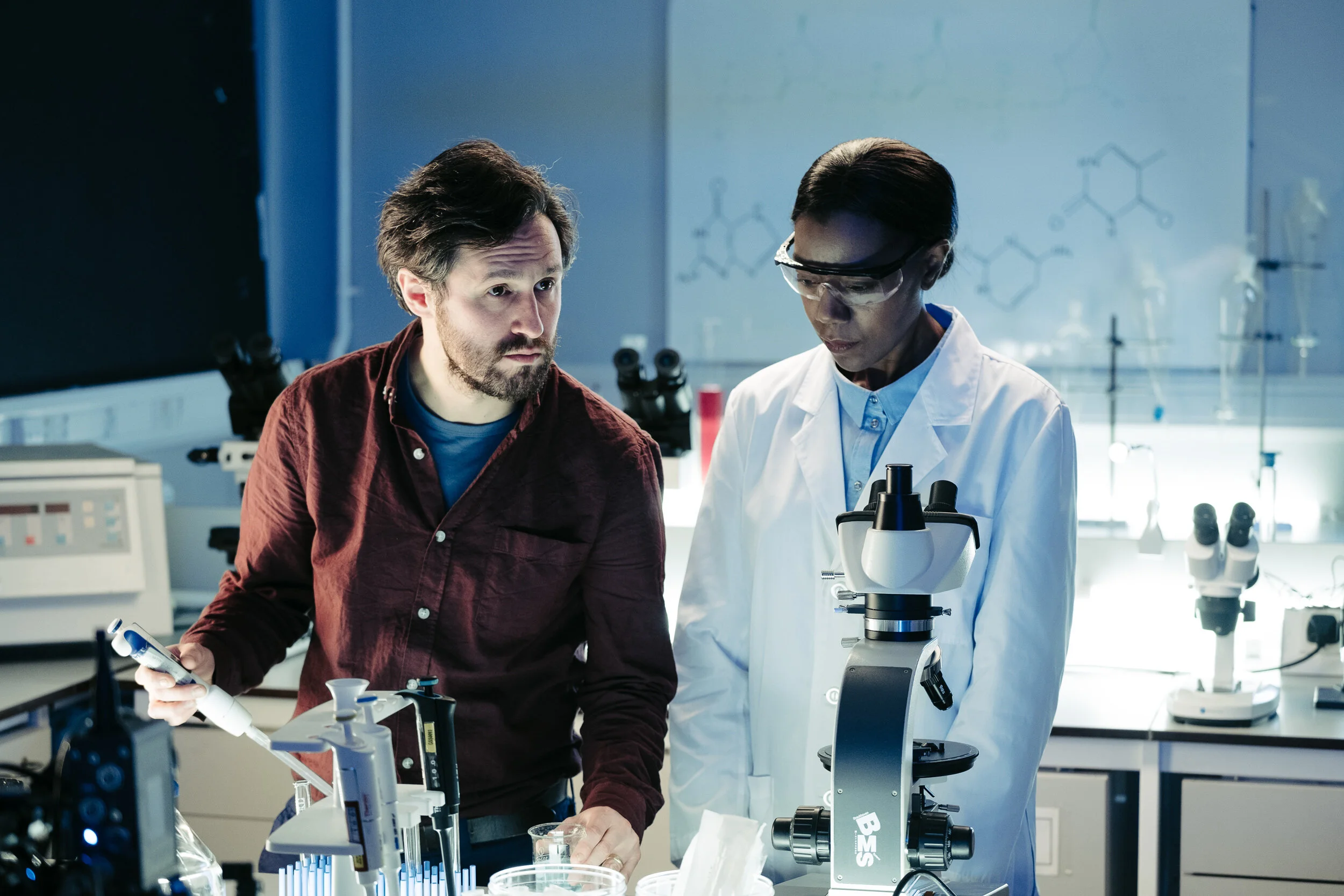 Scientists working together in a laboratory with microscopes and scientific equipment.