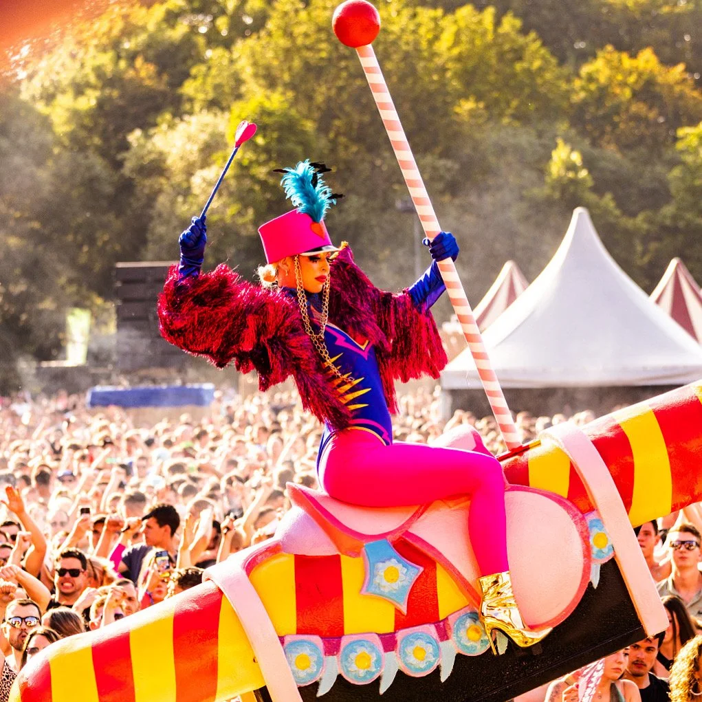 Theatrale performer in kleurrijk kostuum tijdens een festival entertainment show in openlucht.
