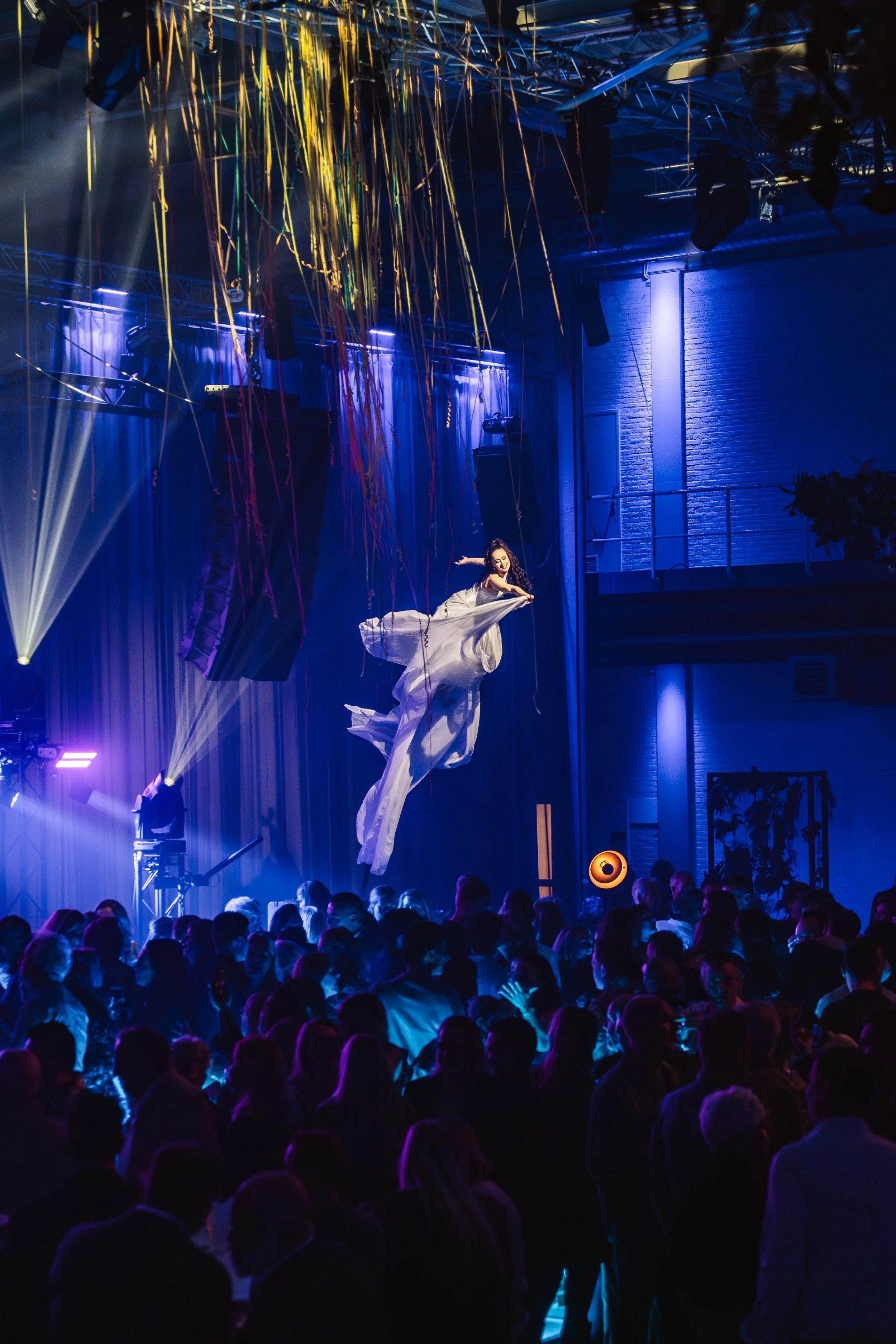 Swaypole artiest in zwierige witte jurk zweeft boven het publiek op een bedrijfsevent