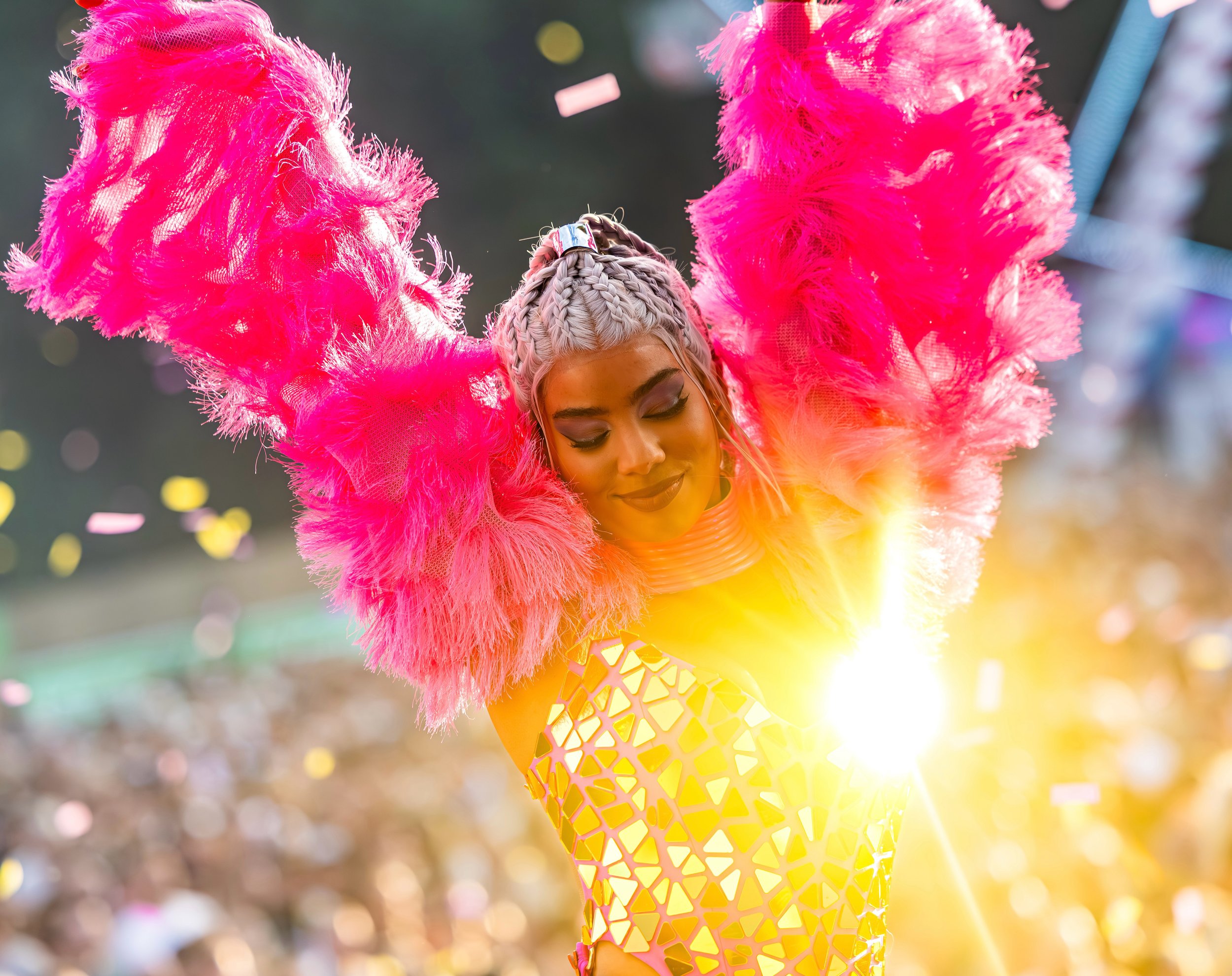Danseres in spiegel outfit met roze en goud voor een grote mensenmassa op een festival