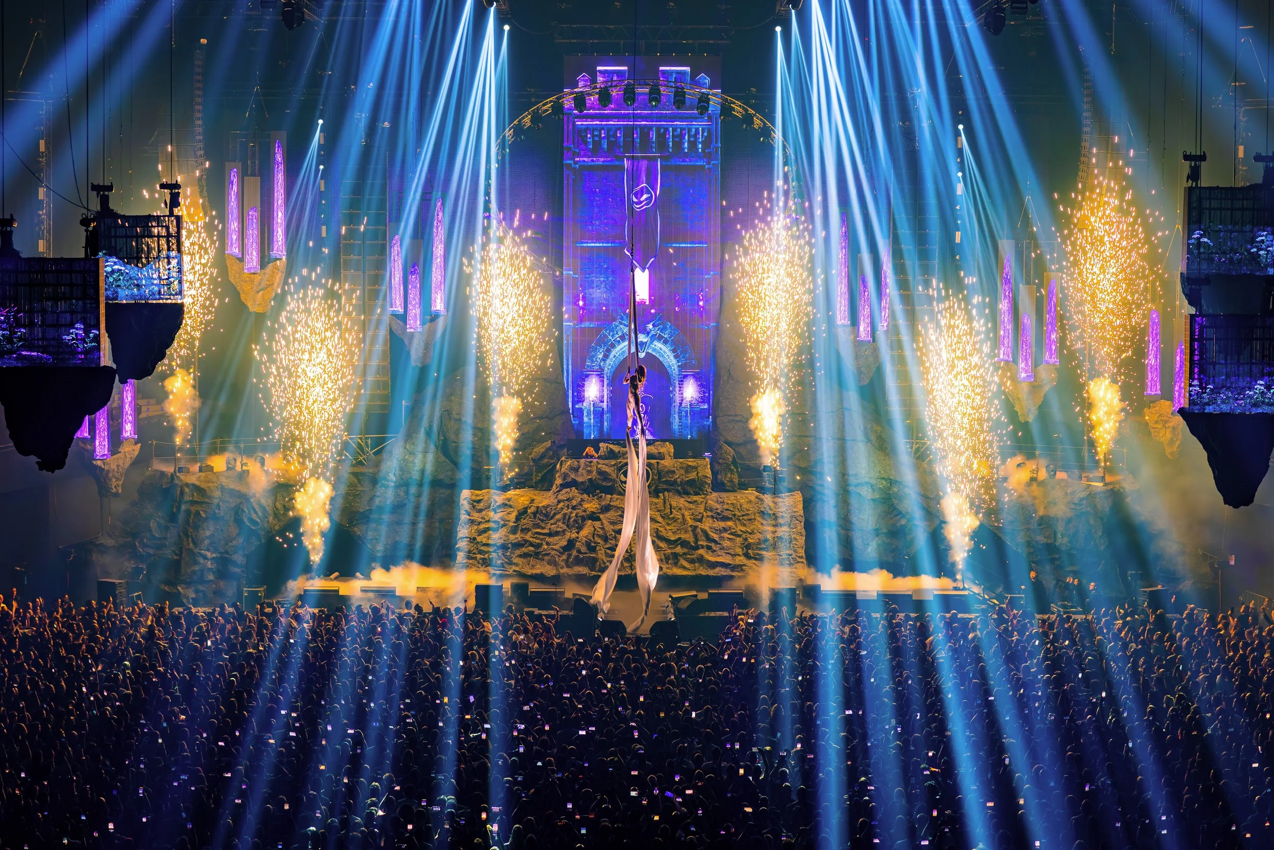 Grootschalige live show productie met aerial silk performer, lichteffecten en stage design tijdens een event.