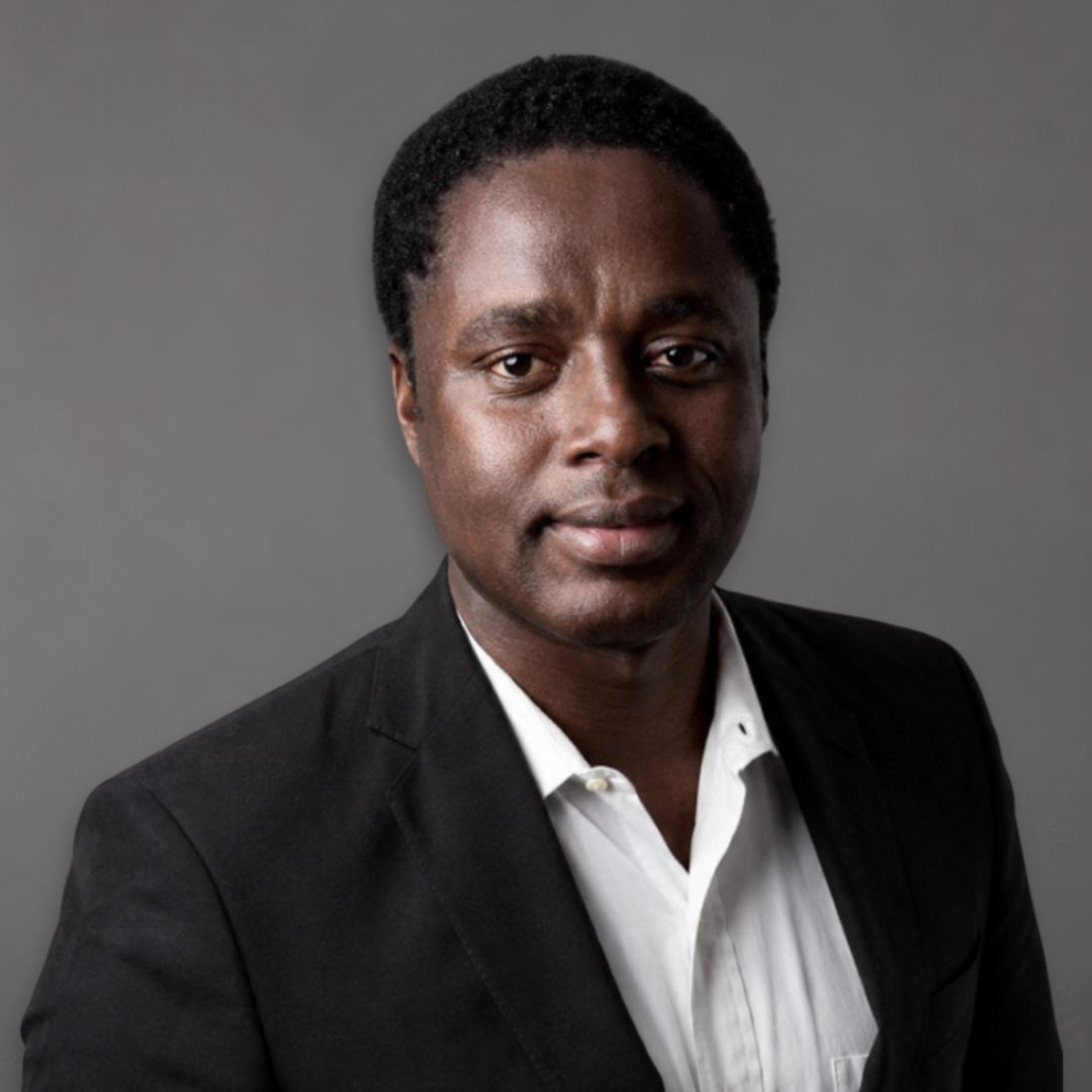 Professional portrait of a Black man in a black suit and white shirt, against a plain light background.