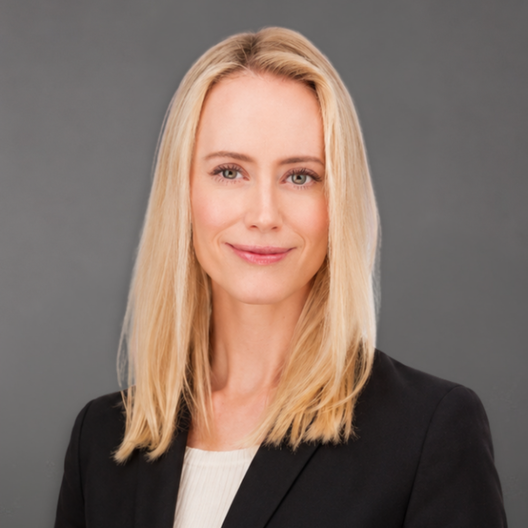A portrait of a woman with long blonde hair, wearing a black blazer, smiling softly against a plain white background.
