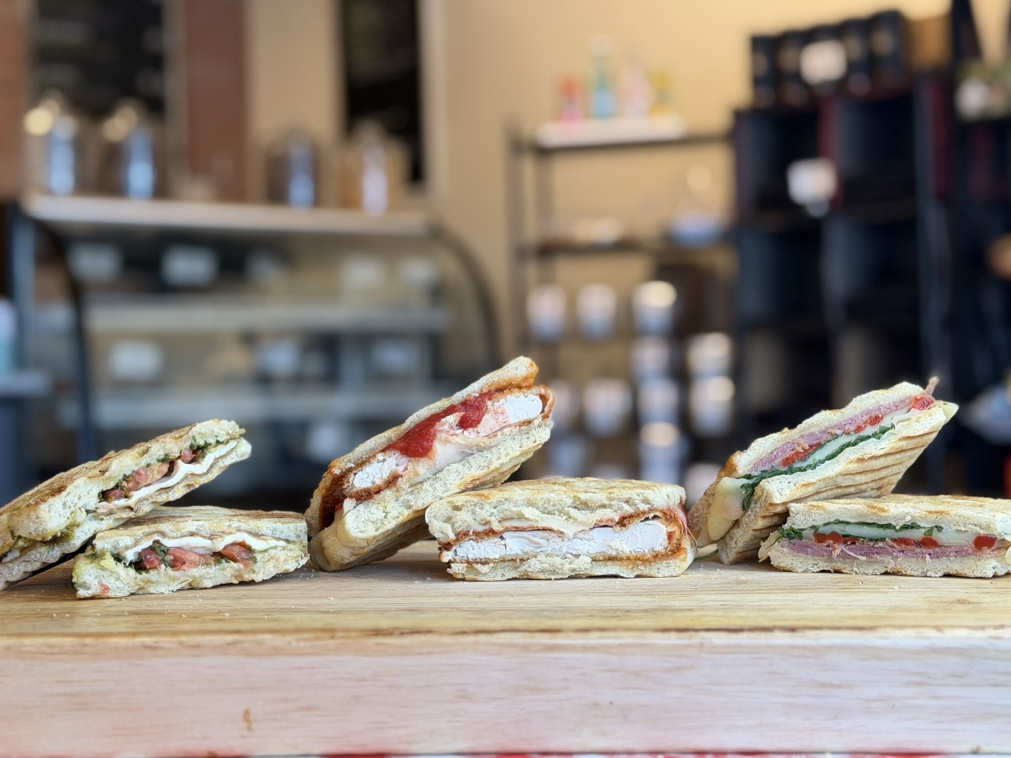Close-up of sliced sandwiches on a wooden surface with blurred restaurant interior in the background.