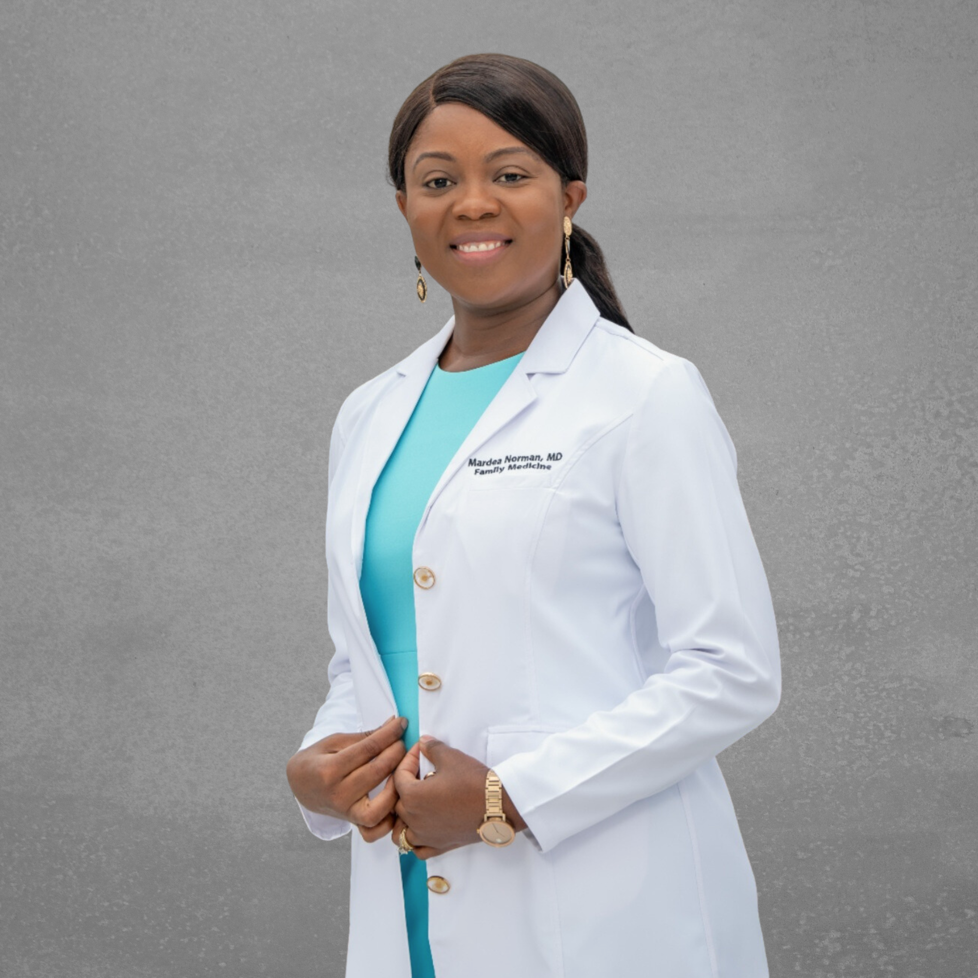 Portrait of a woman in a white lab coat with a name tag that reads 'Mardean Norman, MD, Family Medicine,' Black female doctor, smiling and looking at the camera. Norman family medicine female doctor