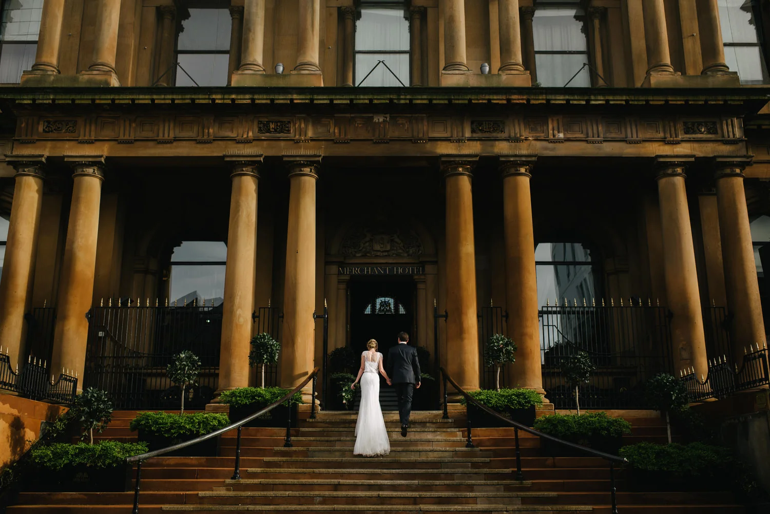 A bride and groom walking up the steps at the beautiful Merchant Hotel in Belfast