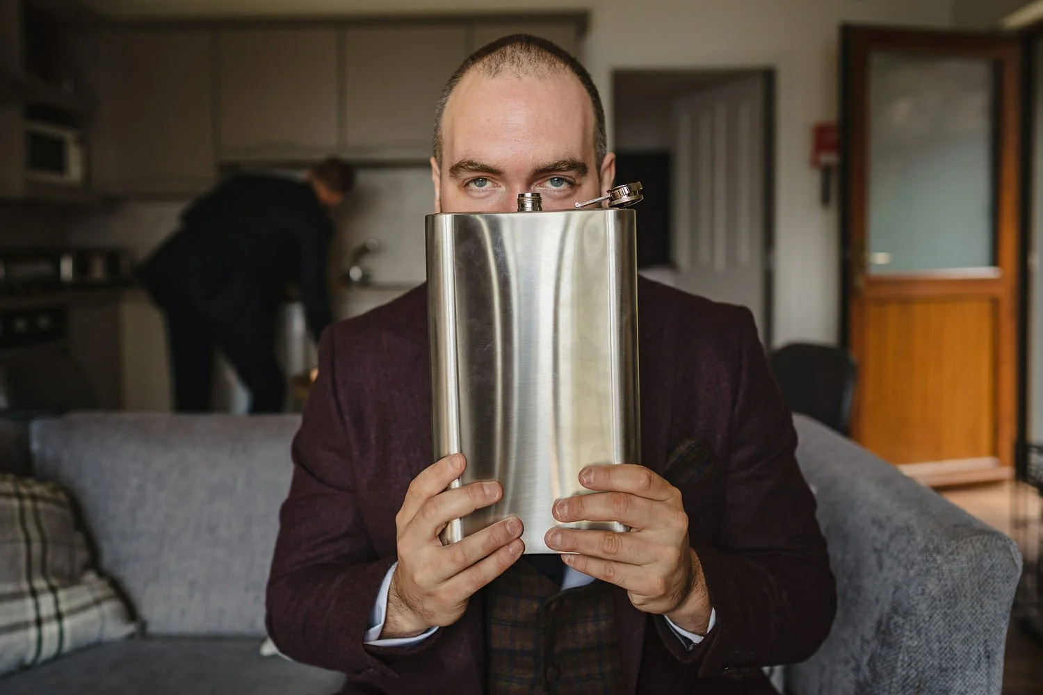 Groom holding a giant hipflask given to him as a quirky funny wedding gift