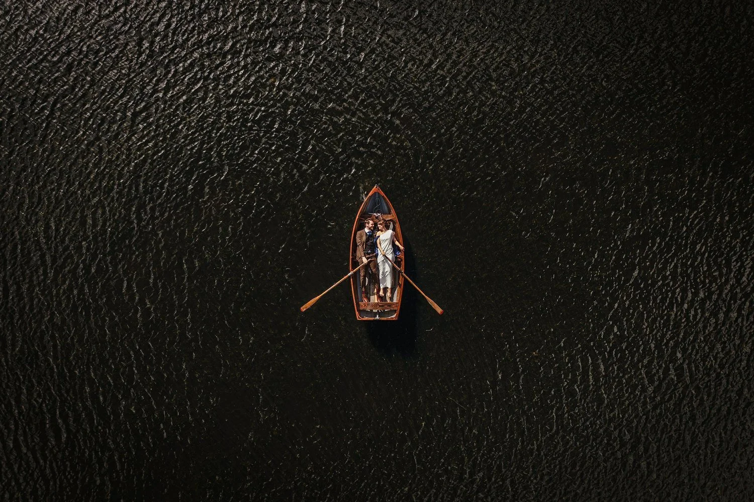 A couple in a row boat at their wedding photographed by a drone from above