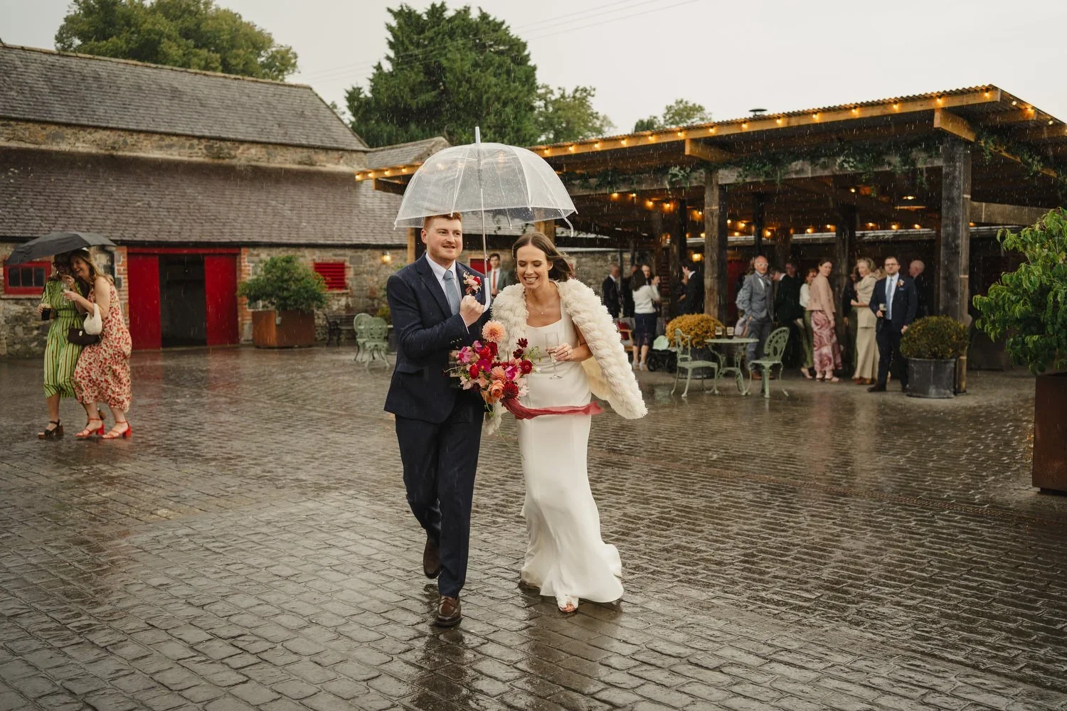 Rainy wedding at Larchfield estate with couple hiding under umbrellas