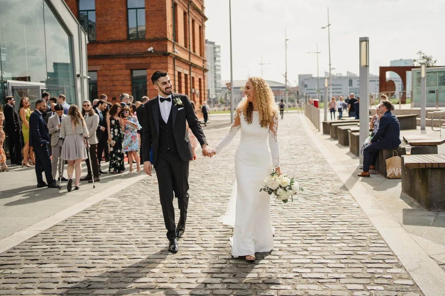 A bride and groom walk along the cobbled streets outside the Titanic Museum