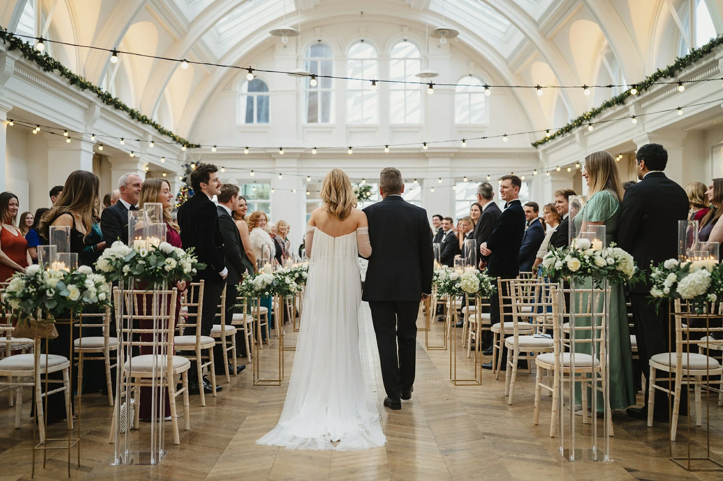 Bride walking up the aisle with her father as guests watch on a New Years Eve wedding in Titanic Hotel Belfast