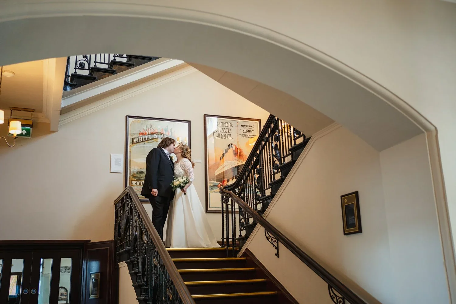 A bride and groom pose on the stairs at Titanic Hotel Belfast