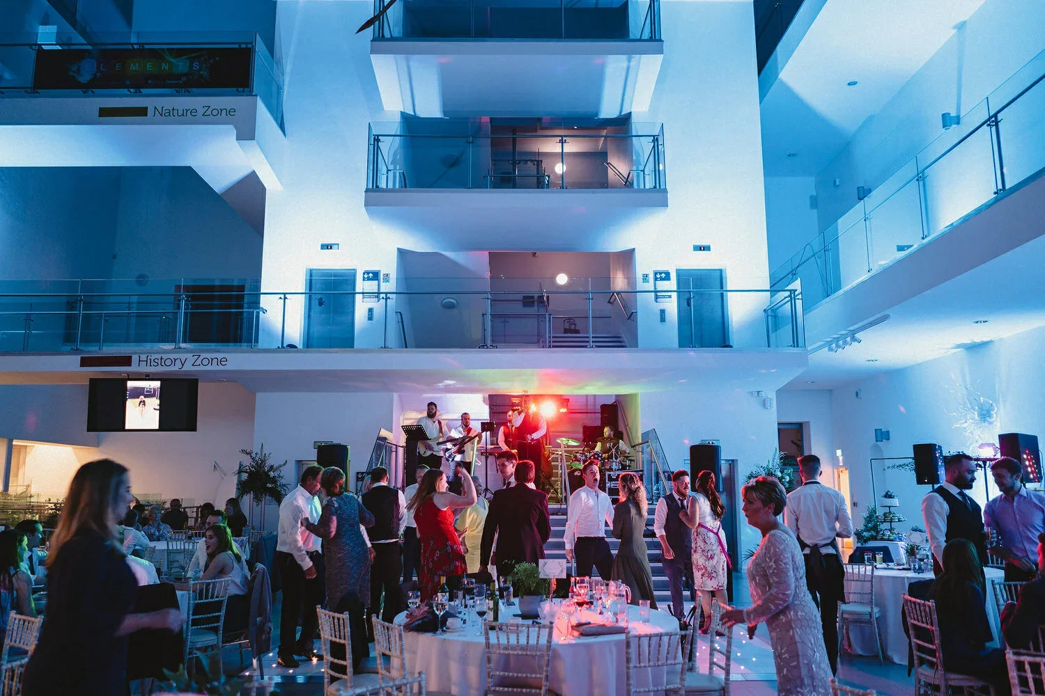Guests dancing at a wedding in Ulster Museum with a full wedding band playing in the backgroun