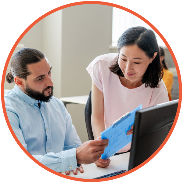 Project manager and colleague engaged in conversation in a office, reviewing documents.